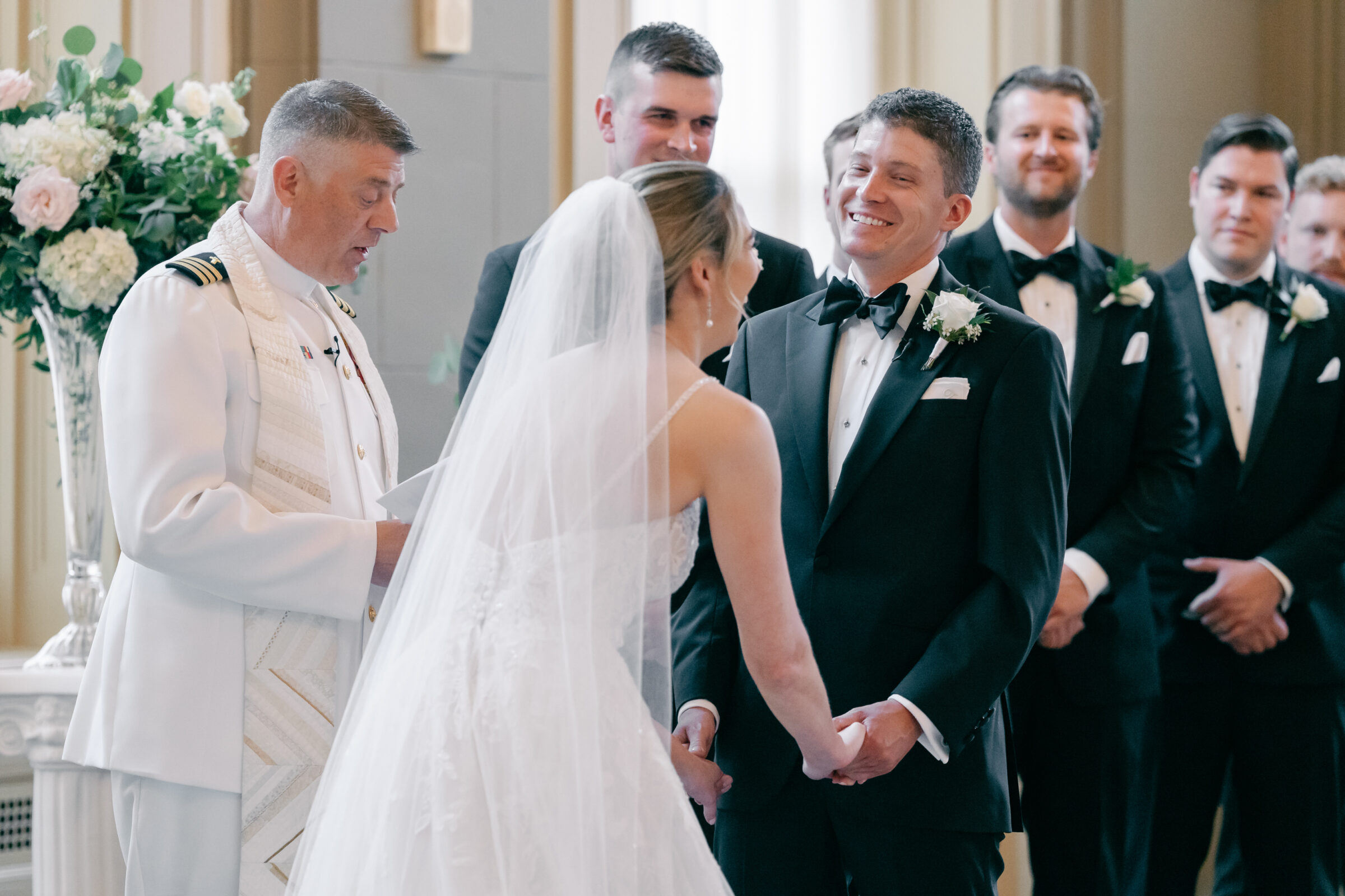 Bride and groom smiling during their wedding ceremony at the Hotel John Marshall in Richmond VA with the officiant leading the vows.