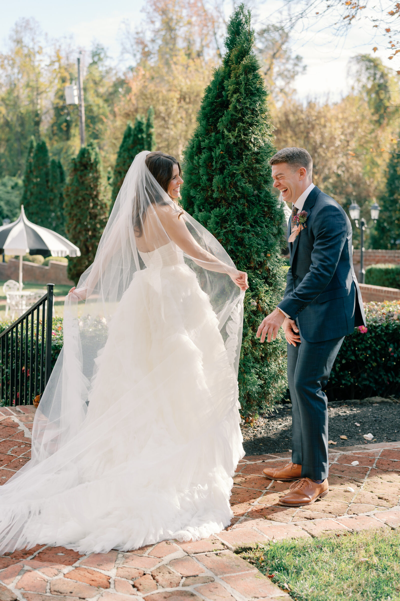 Joyful first look between bride and groom during a Mankin Mansion wedding in Richmond VA, with the bride’s veil flowing in the garden courtyard.
