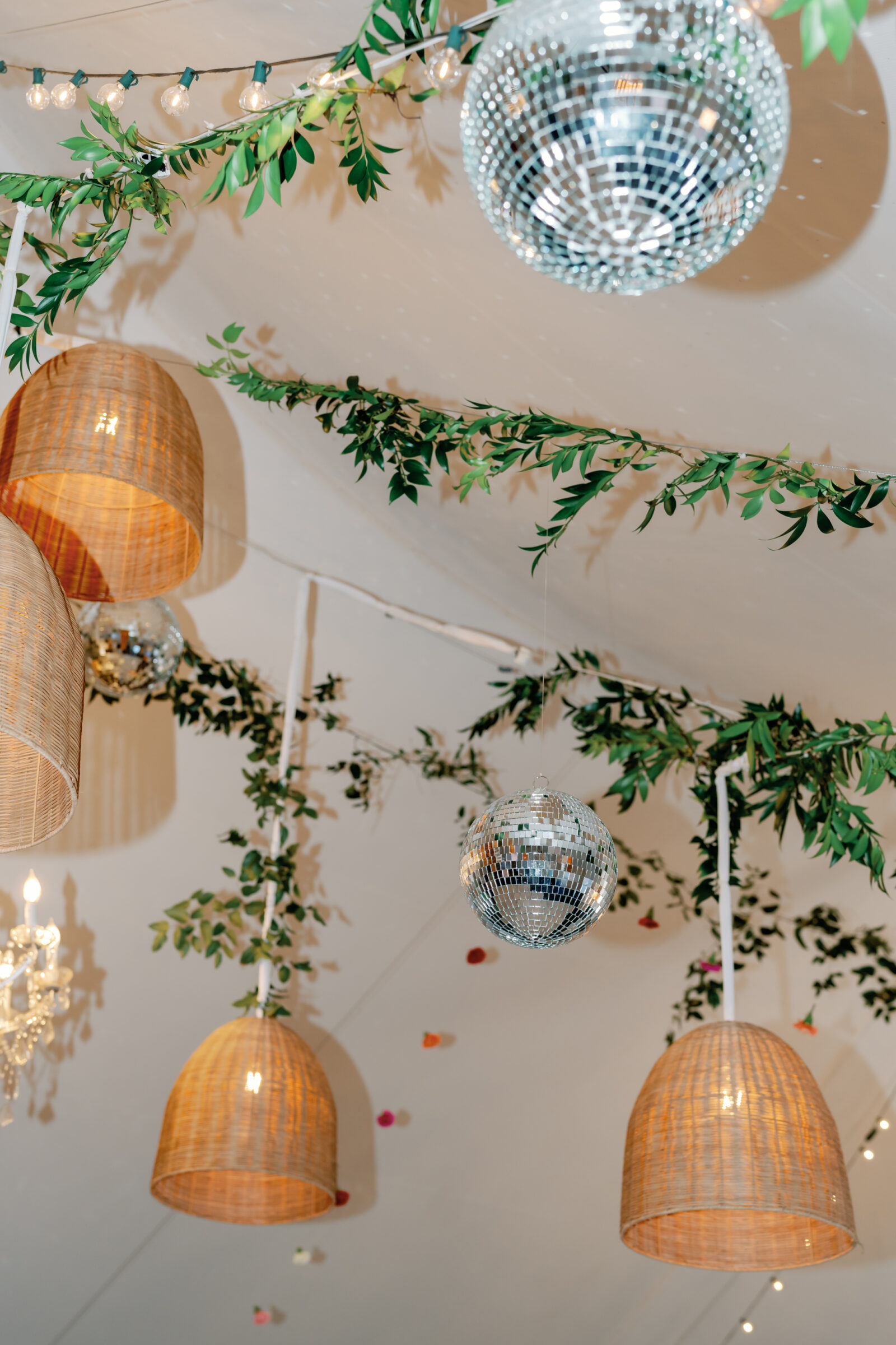 Wedding reception décor in Richmond VA with disco balls, woven lanterns, greenery, and string lights hanging inside the tent.