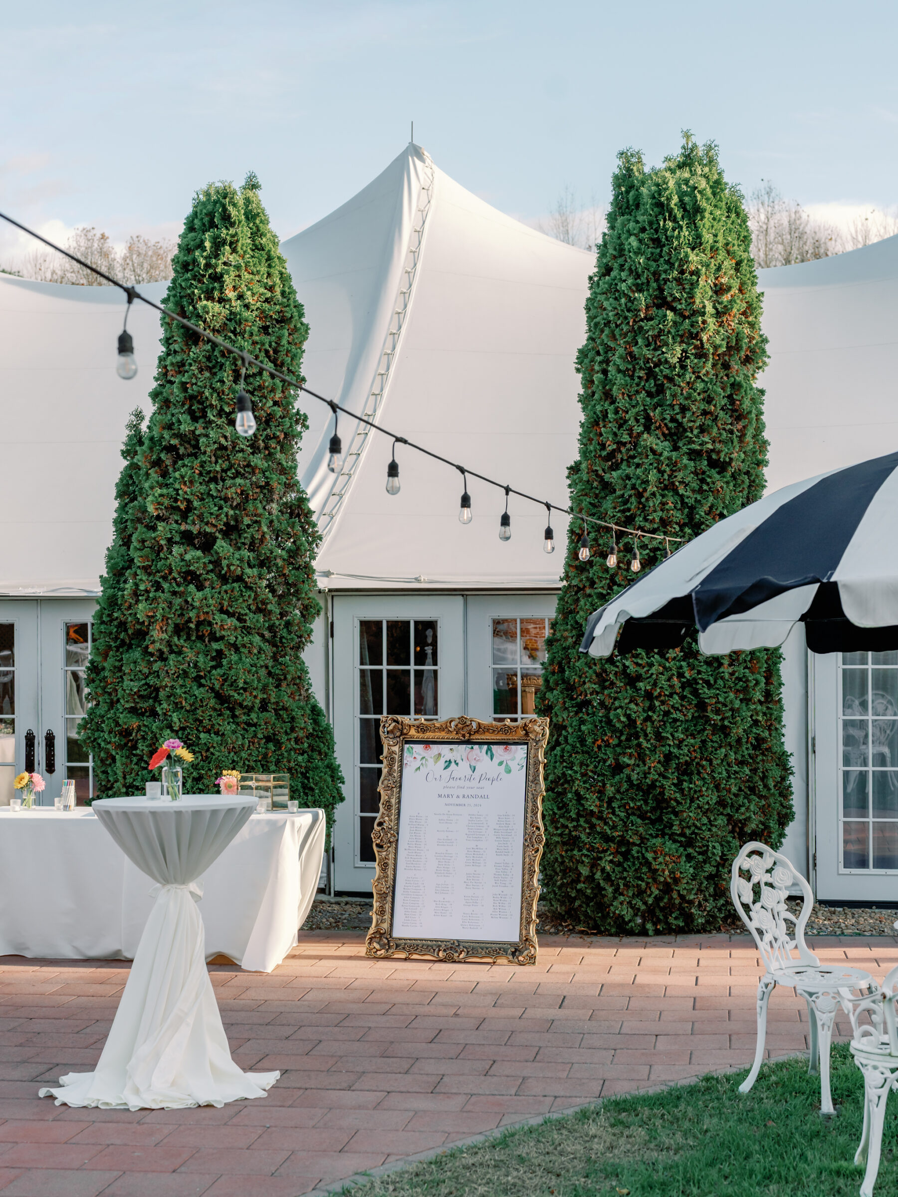 Cocktail hour setup outside the European Gallery Tent at Mankin Mansion in Richmond VA with seating chart, bistro tables, and string lights.