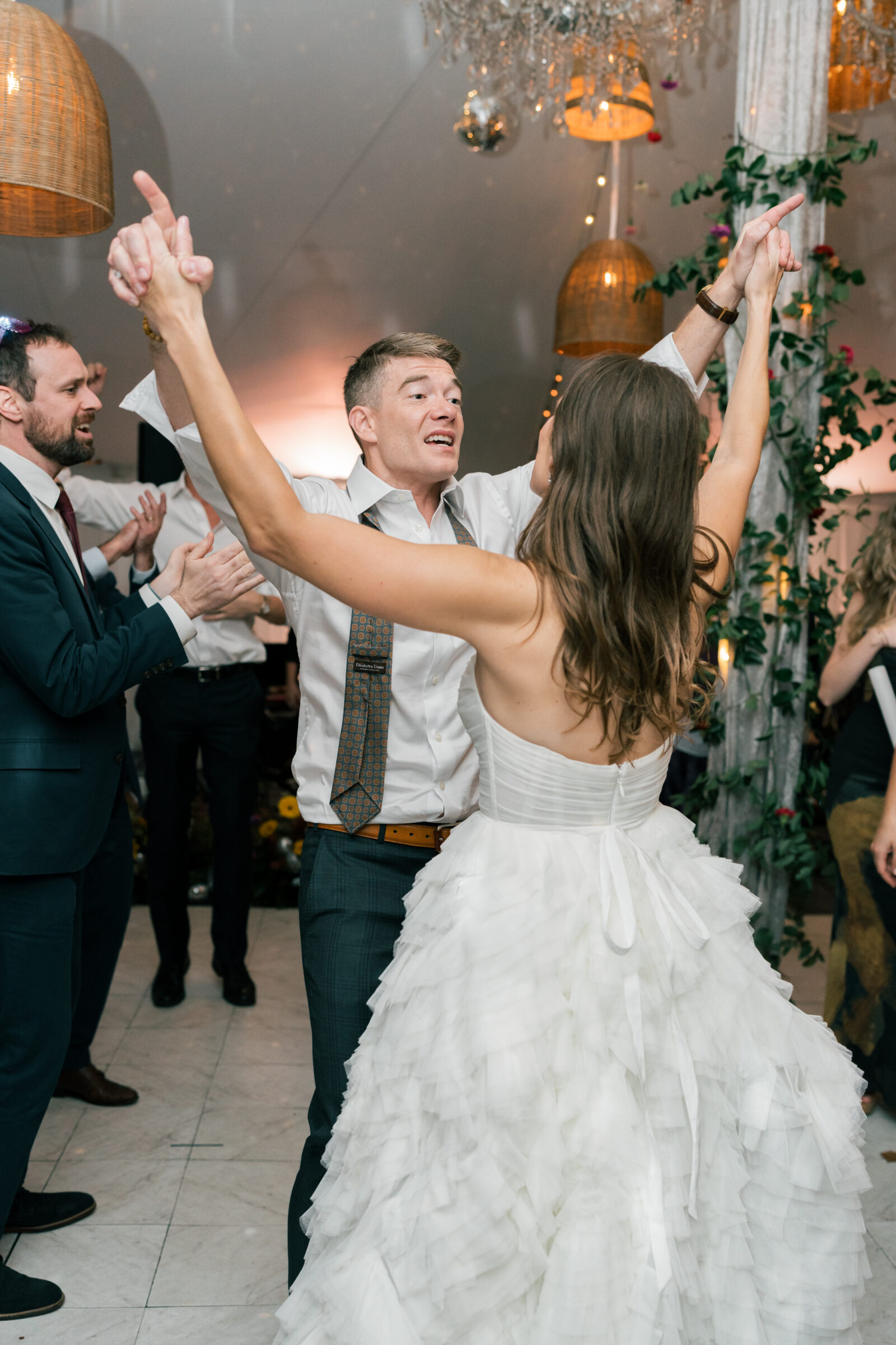 Bride and groom celebrating on the dance floor during their Mankin Mansion wedding reception in Richmond VA, surrounded by guests under chandeliers and lanterns.