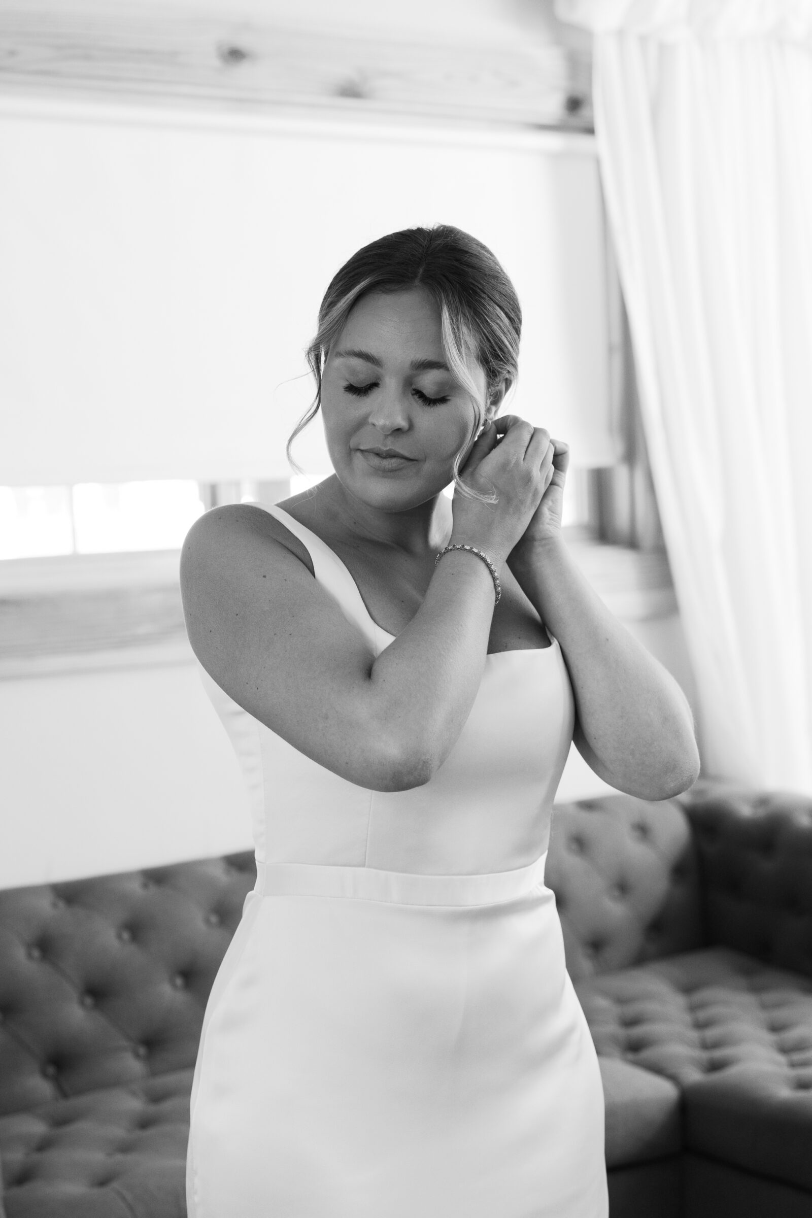 Bride adjusts an earring in a satin gown while getting ready for a wedding at Middleburg Barn.