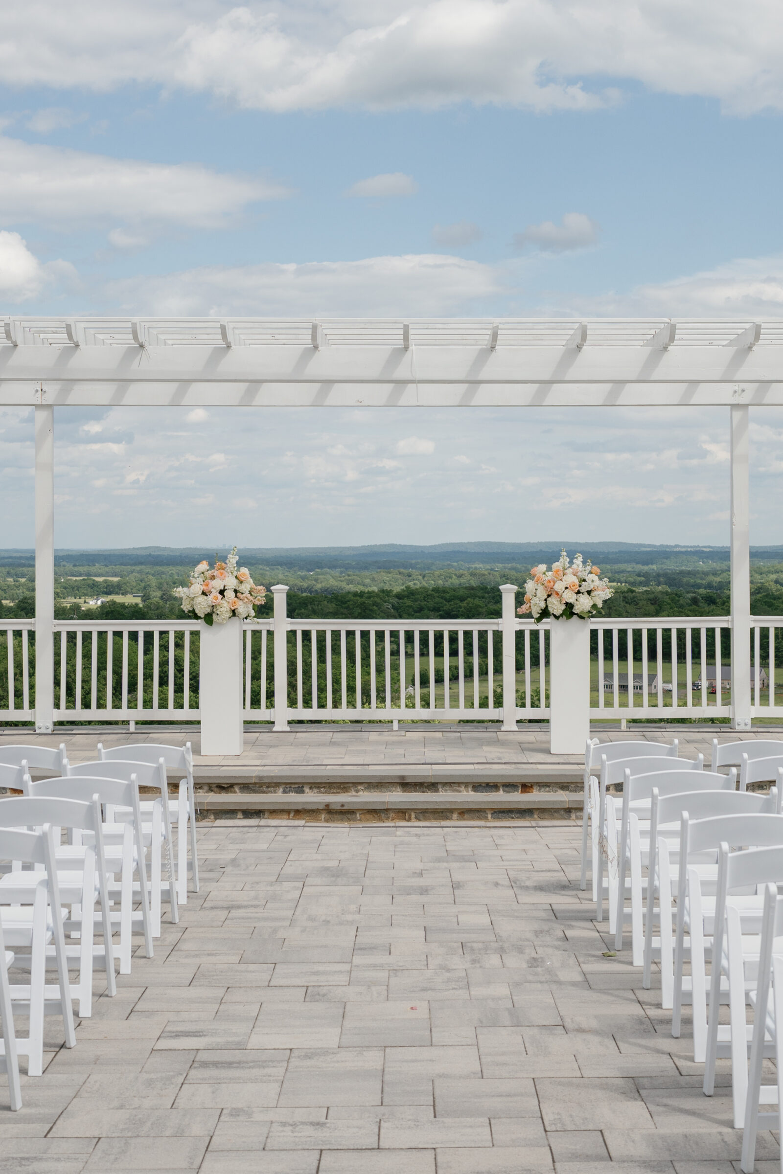 Grand Patio ceremony setup at The View at Bluemont with a white pergola, pastel floral arrangements, and sweeping Blue Ridge Mountain views at a Northern VA wedding venue.