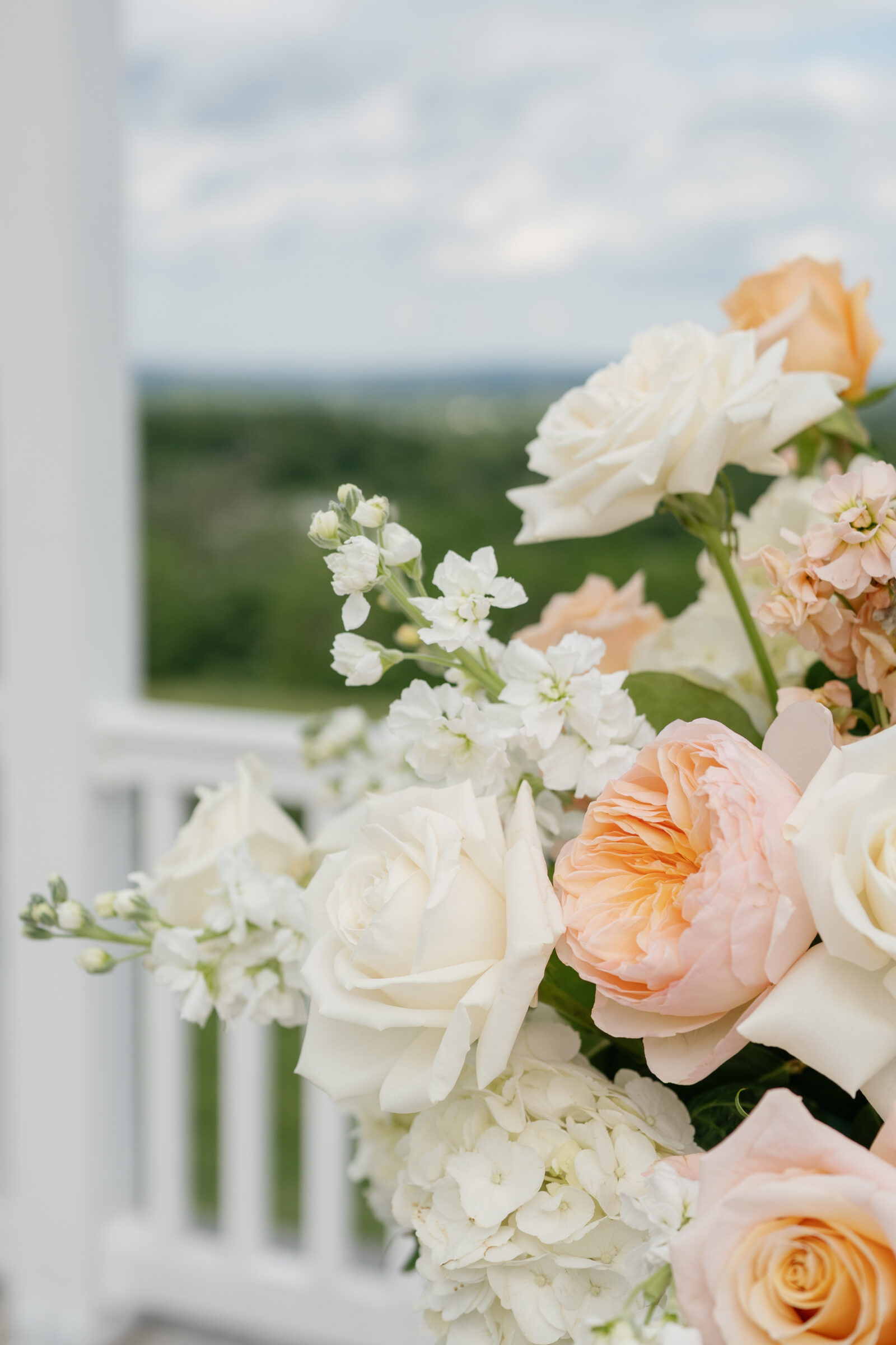Spring wedding flowers with ivory roses, peach garden roses, and white hydrangeas decorating a Northern VA wedding venue.