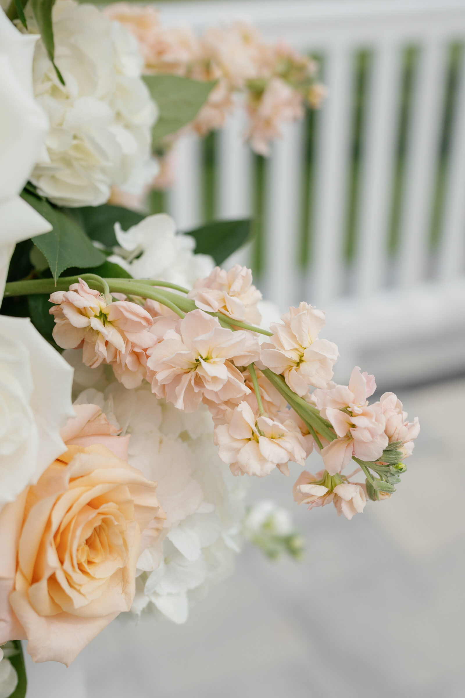 Blush stock flowers, peach roses, and white hydrangeas in a ceremony arrangement