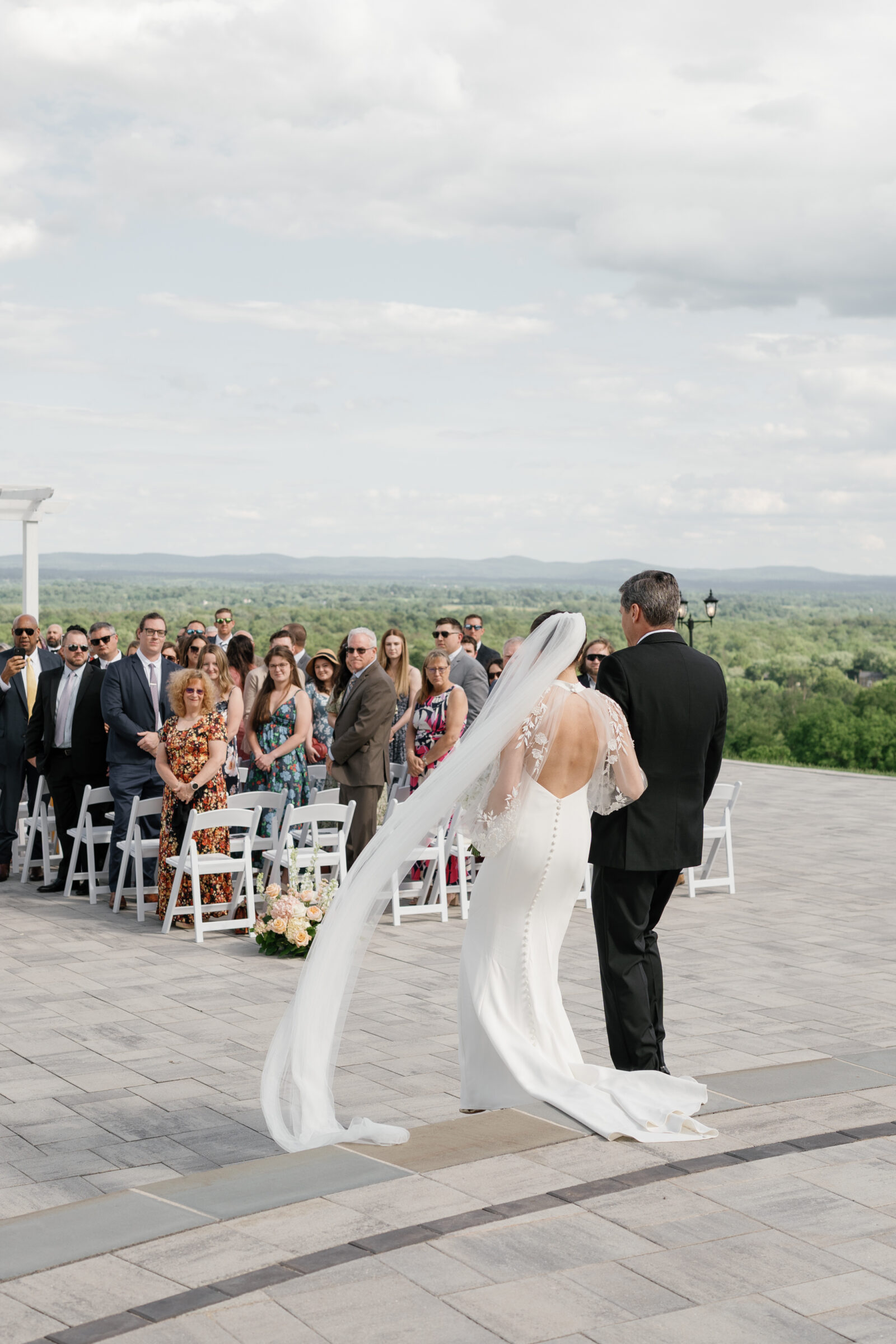 Bride with a flowing veil walking down the aisle on the Grand Patio at The View at Bluemont, a Northern VA wedding venue with sweeping mountain views.