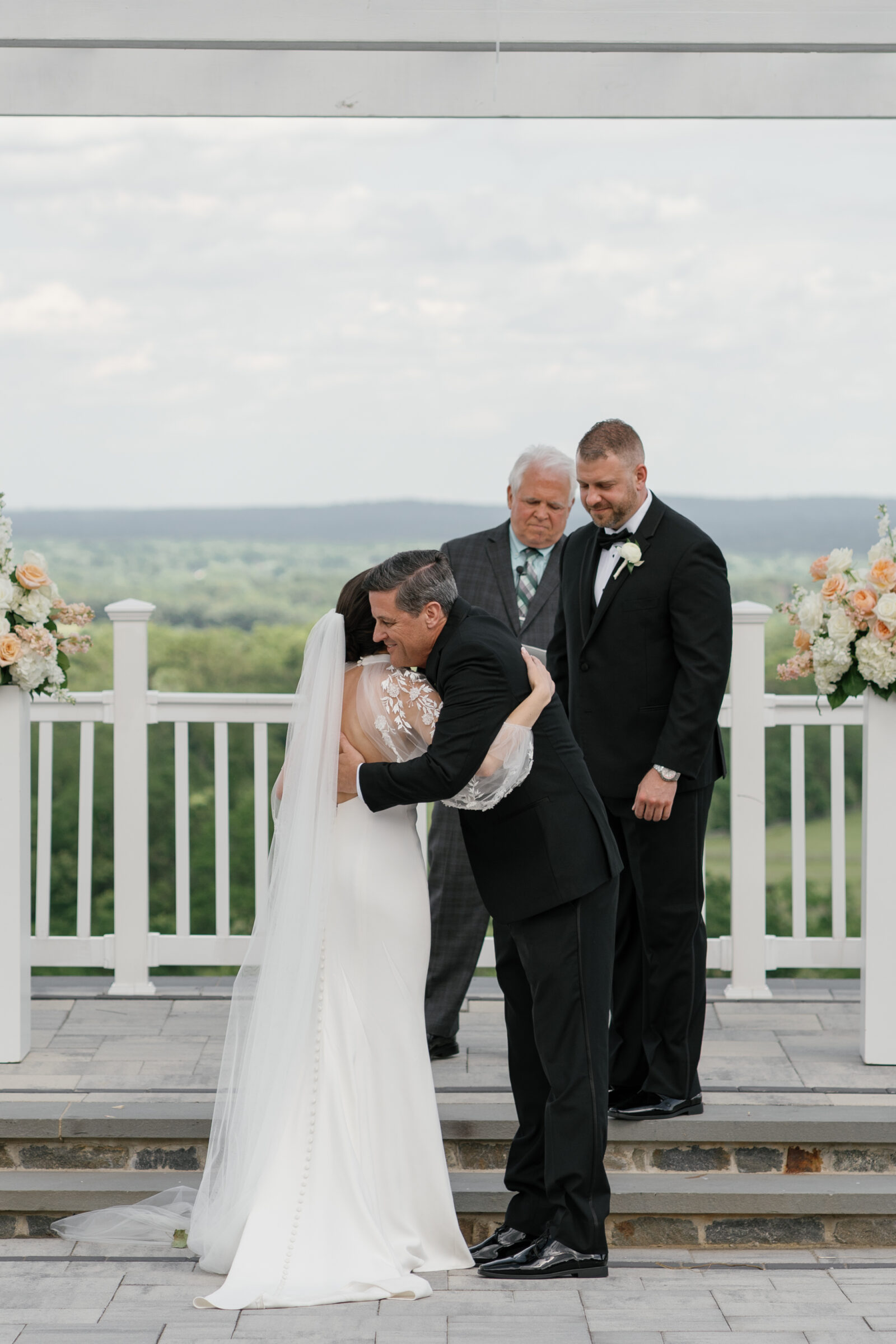 Father embracing the bride at the altar during a Grand Patio ceremony at The View at Bluemont, a Northern VA wedding venue with mountain views.