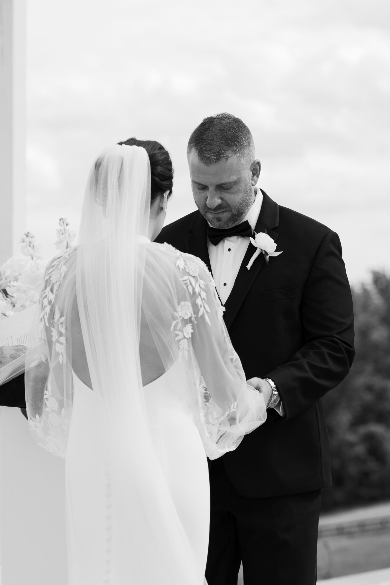 Bride and groom holding hands and bowing their heads during vows on the Grand Patio at The View at Bluemont, a Northern VA wedding venue.