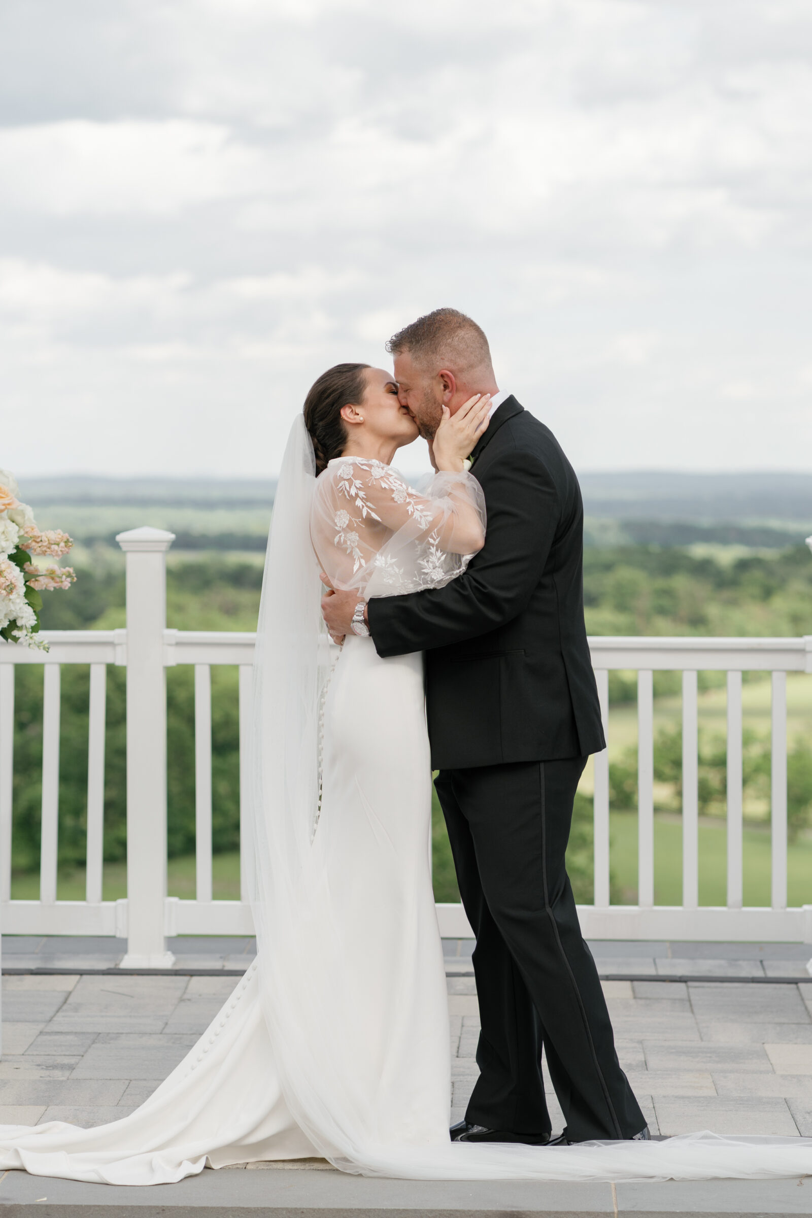 Bride and groom sharing their first kiss as newlyweds on the Grand Patio at The View at Bluemont, a Northern VA wedding venue with mountain views.