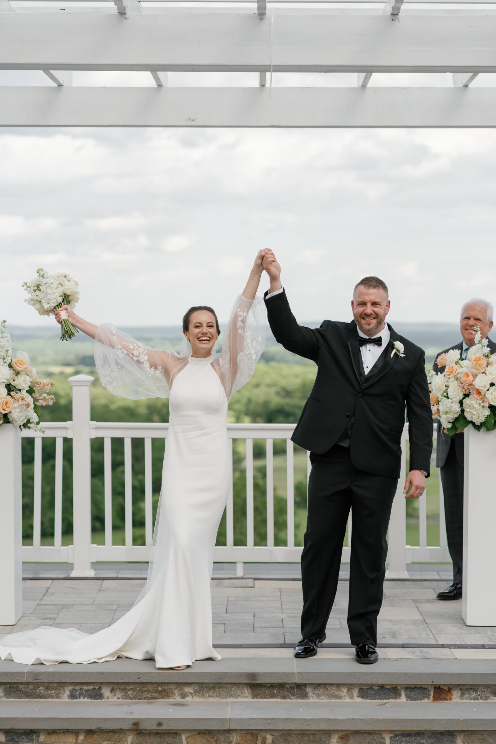 Newlyweds celebrating with raised hands after their ceremony on the Grand Patio at The View at Bluemont, a Northern VA wedding venue with mountain views.