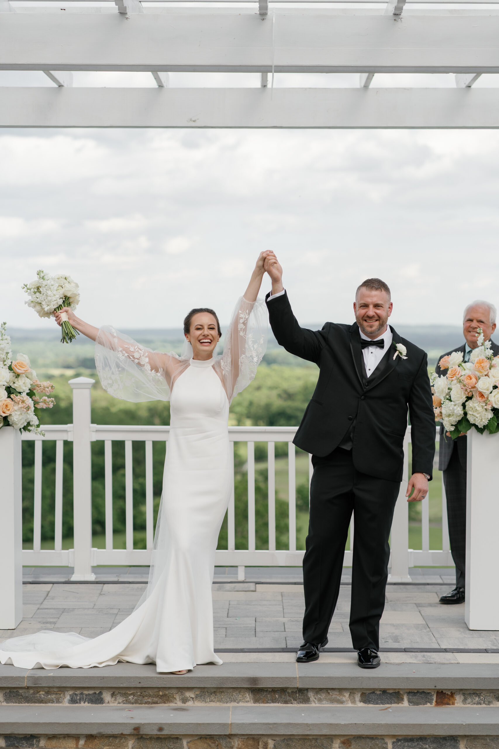 Newlyweds celebrating with raised hands after their ceremony on the Grand Patio at The View at Bluemont, a Northern VA wedding venue with mountain views.