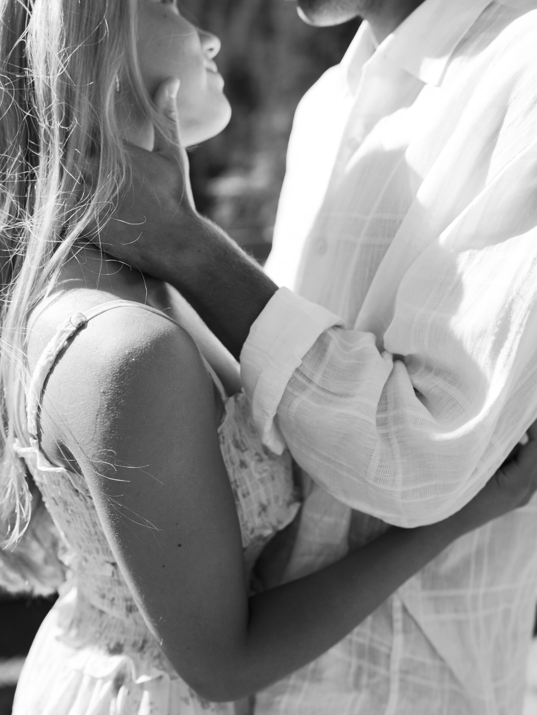 Black and white detail of an intimate moment during an Umpqua River engagement session, as the groom-to-be gently holds his fiancée's face in soft light.