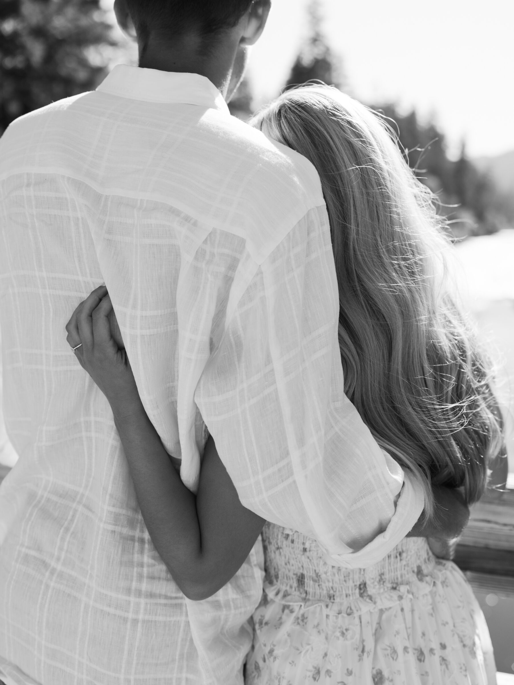 Black and white photo of a couple embracing during their Umpqua River engagement session, with the bride-to-be resting her head on her fiancé’s shoulder.