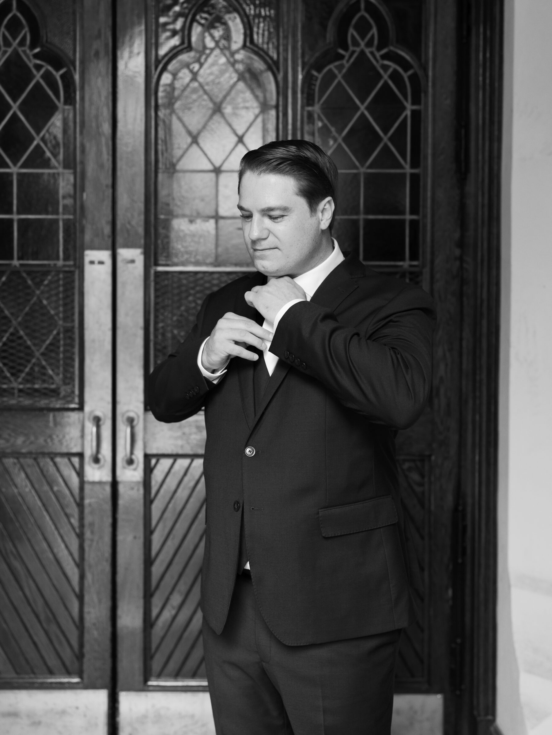 Groom adjusting his tie outside Dahlgren Chapel at Georgetown University before a Catholic ceremony in Washington DC.