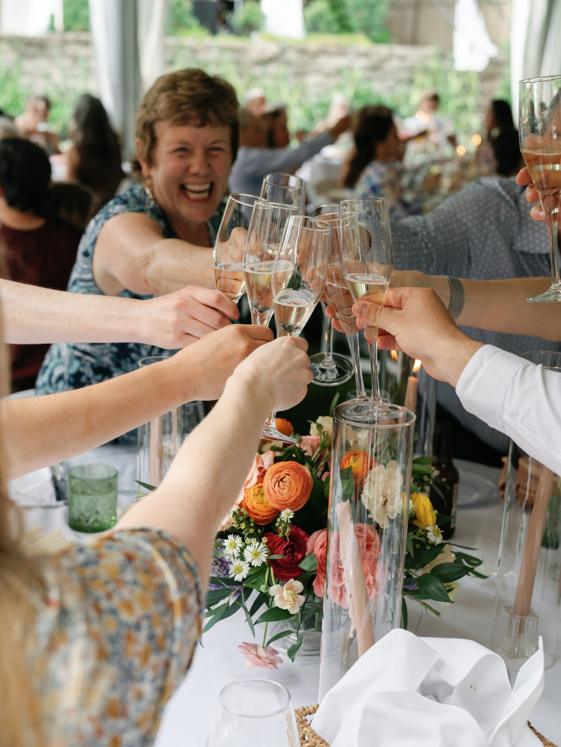 Guests raising champagne glasses in a celebratory toast around floral centerpieces inside the tented lawn reception at a Woodrow Wilson House Wedding in Washington DC.
