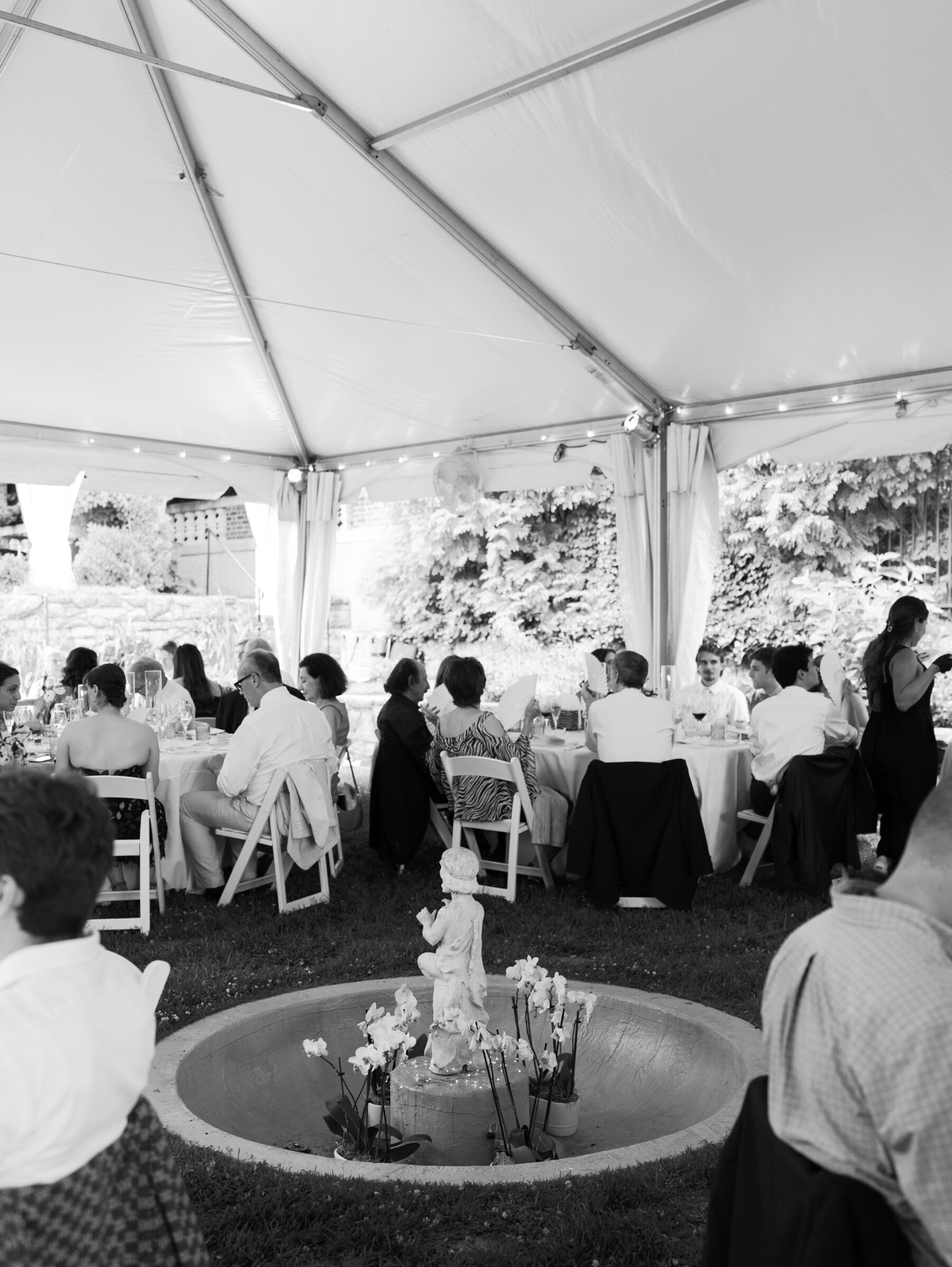 Guests seated at round tables inside the tented lawn reception space with garden fountain detail at a Woodrow Wilson House Wedding in Washington DC.