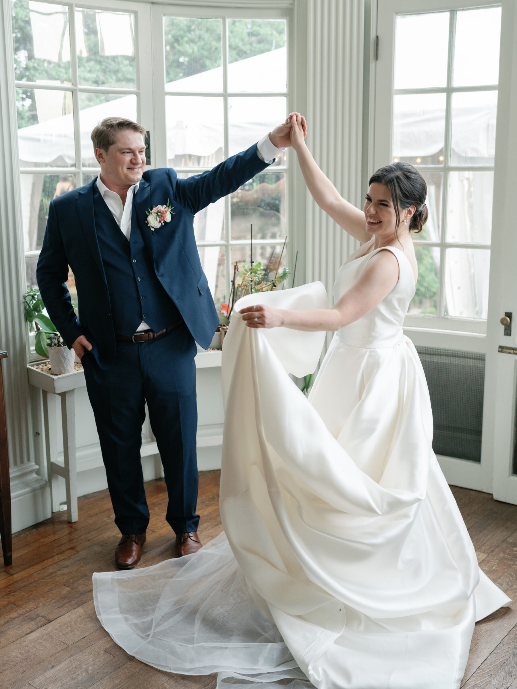 Bride and groom sharing a joyful dance inside the historic Woodrow Wilson House with garden views and tented reception visible through the windows.