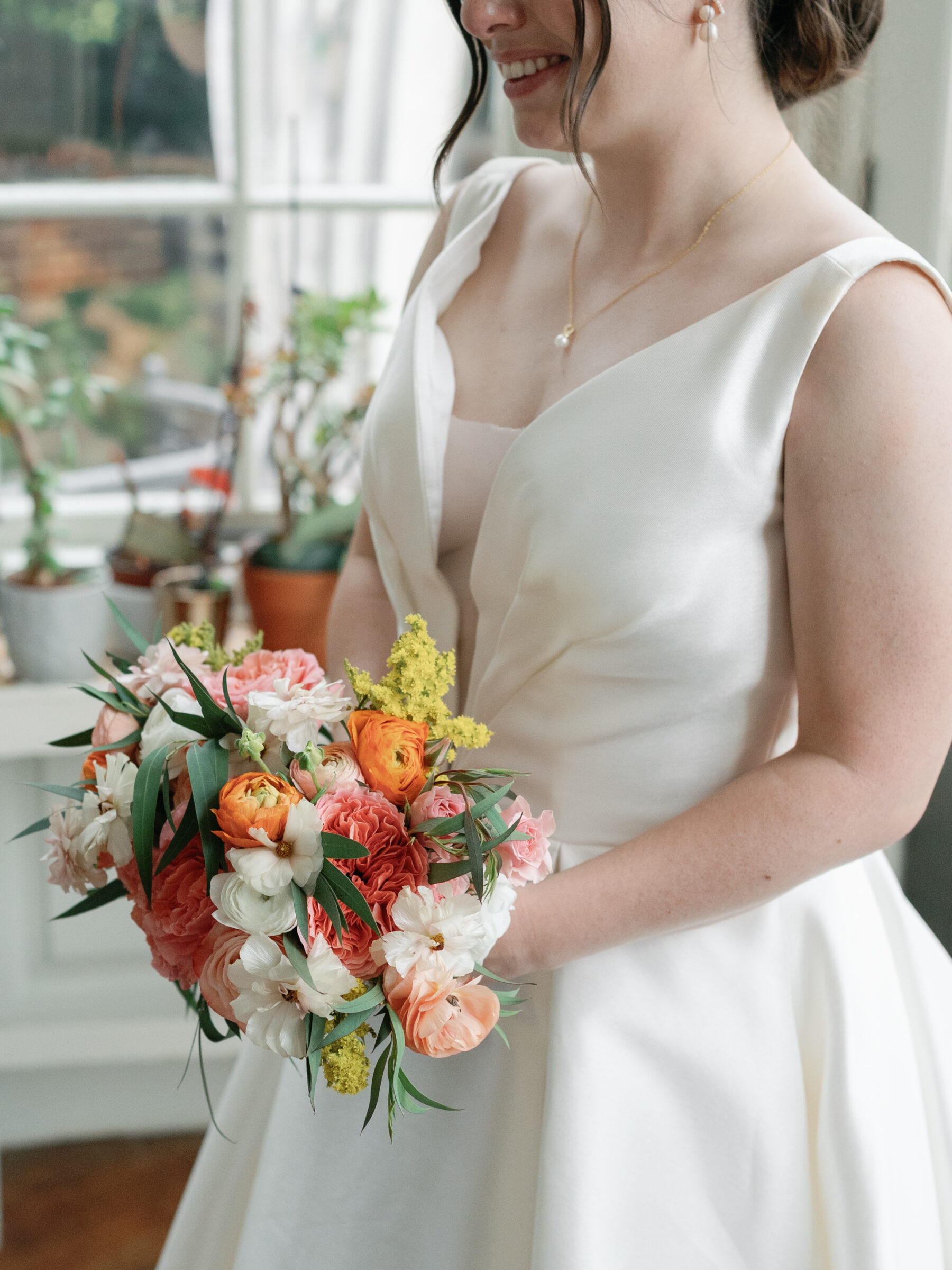 Bride holding a vibrant bouquet of pink, coral, and orange flowers inside the historic Woodrow Wilson House during her Washington DC wedding.