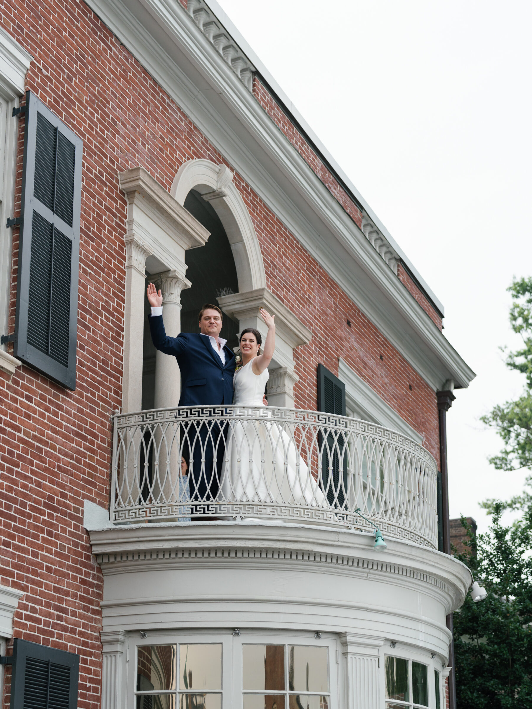 Bride and groom waving to guests from the historic balcony of the Woodrow Wilson House Wedding venue in Washington DC.