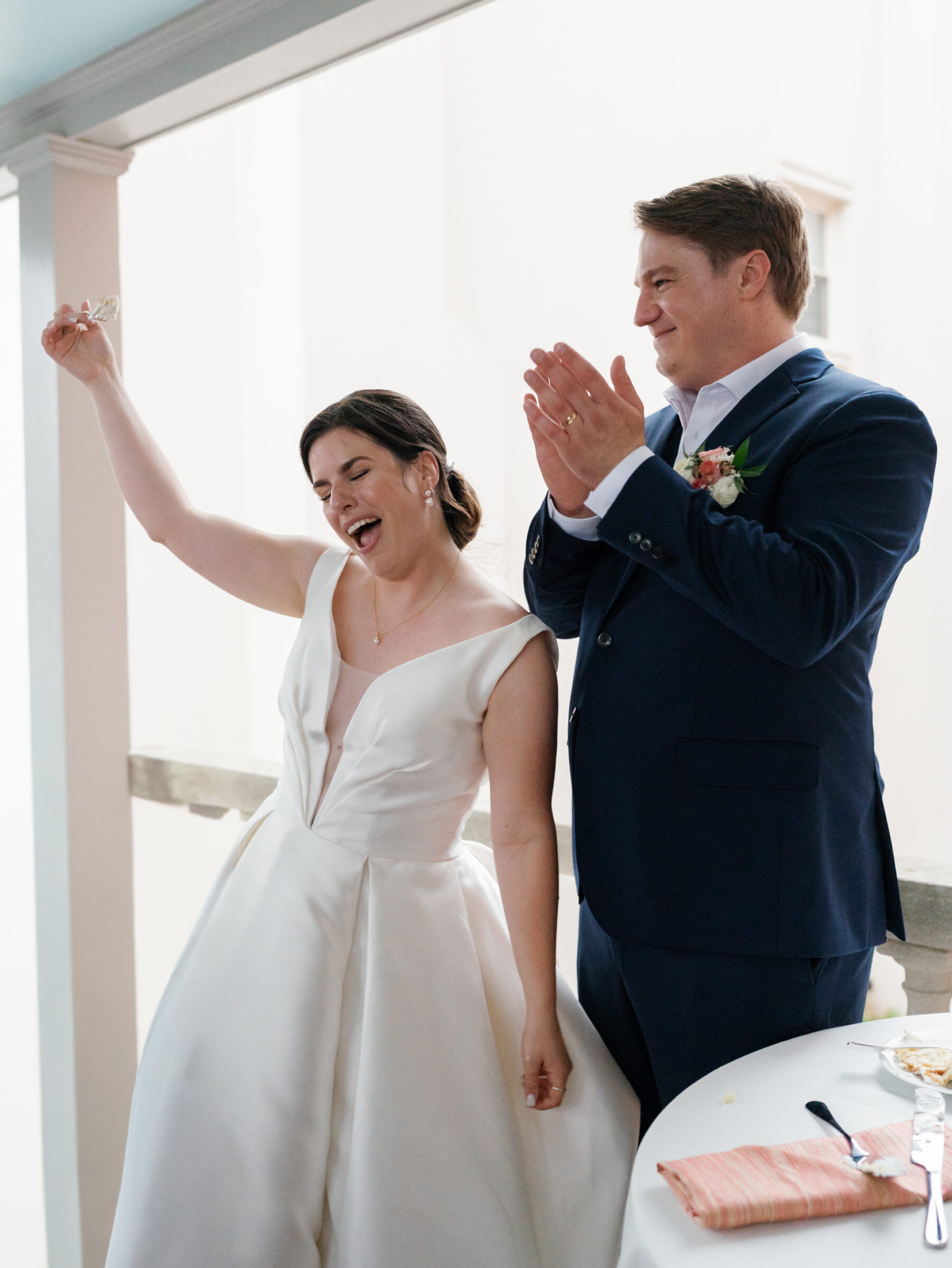 Bride and groom celebrating joyfully after cutting their wedding cake at the Woodrow Wilson House in Washington DC.