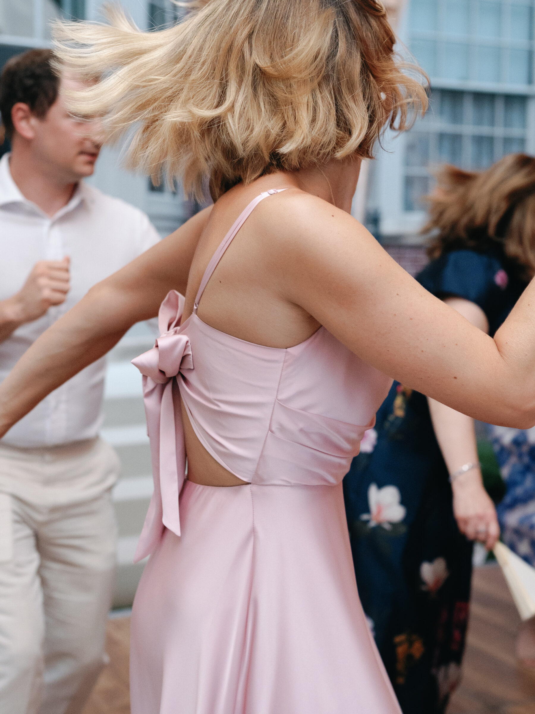 Guest in a flowing pink bridesmaid dress dancing with joyful movement during wedding reception in Georgetown DC.