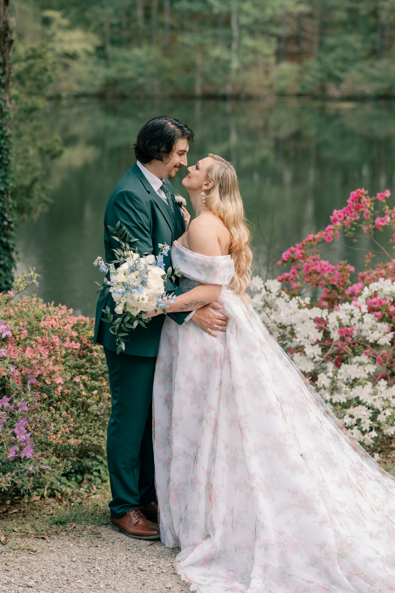 Bride and groom share a romantic moment by the lake in Columbia, Virginia, surrounded by blooming spring flowers during their vineyard wedding.