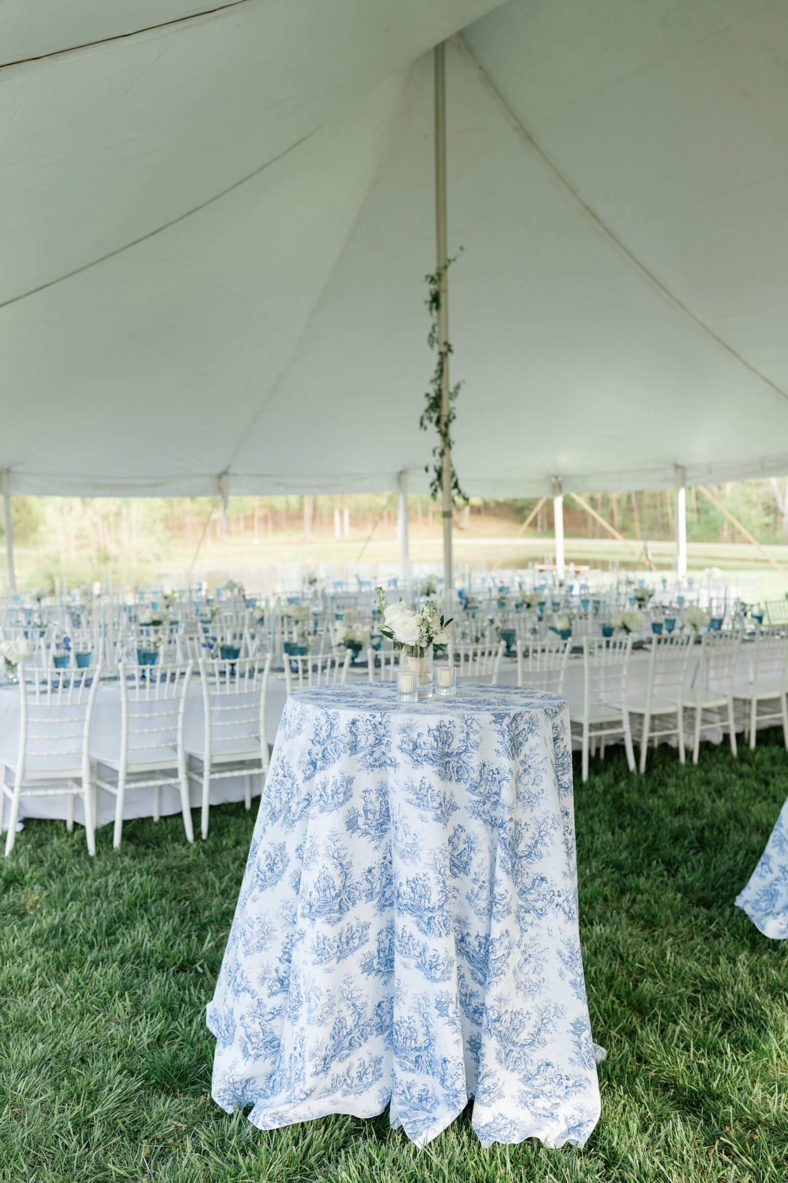 Wedding reception under a tent at Rassawek Vineyards in Virginia, featuring white chairs, blue and white patterned linens, and floral centerpieces for an elegant vineyard celebration.