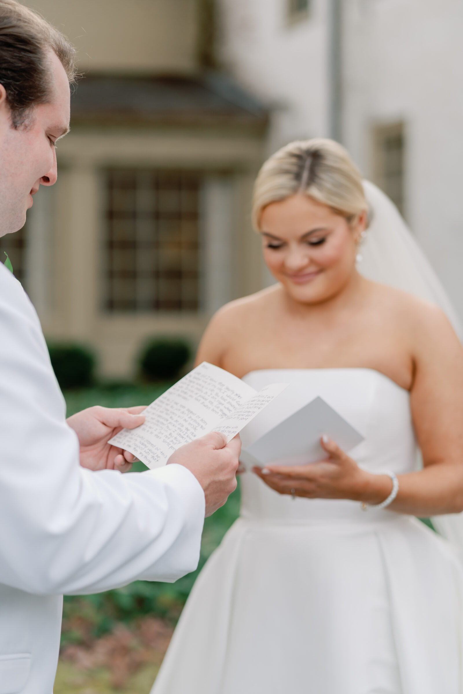 Bride and groom sharing personal vows during their Williamsburg Inn wedding, with the groom reading from handwritten notes while the bride smiles and holds a card.
