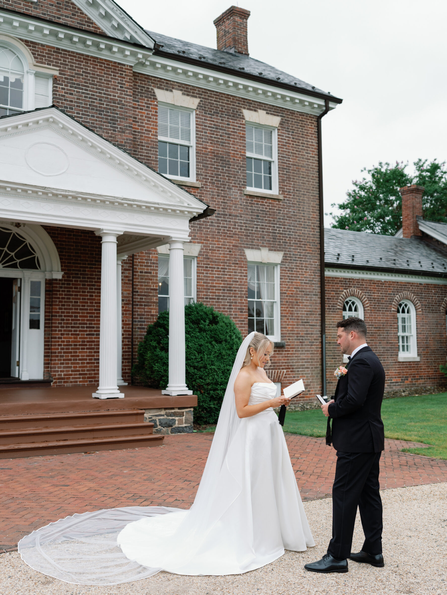 Bride and groom reading vows during a private first look outside the historic manor house at Belmont Country Club in Ashburn, VA.