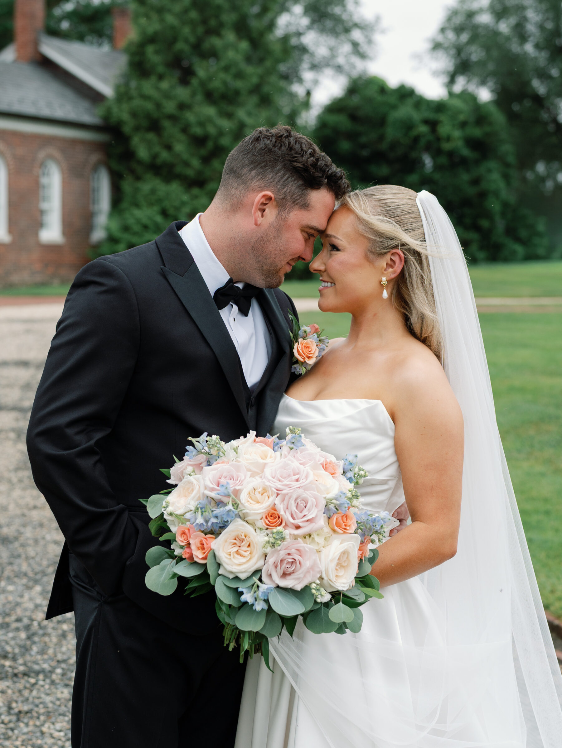 Bride and groom embracing with pastel rose bouquet