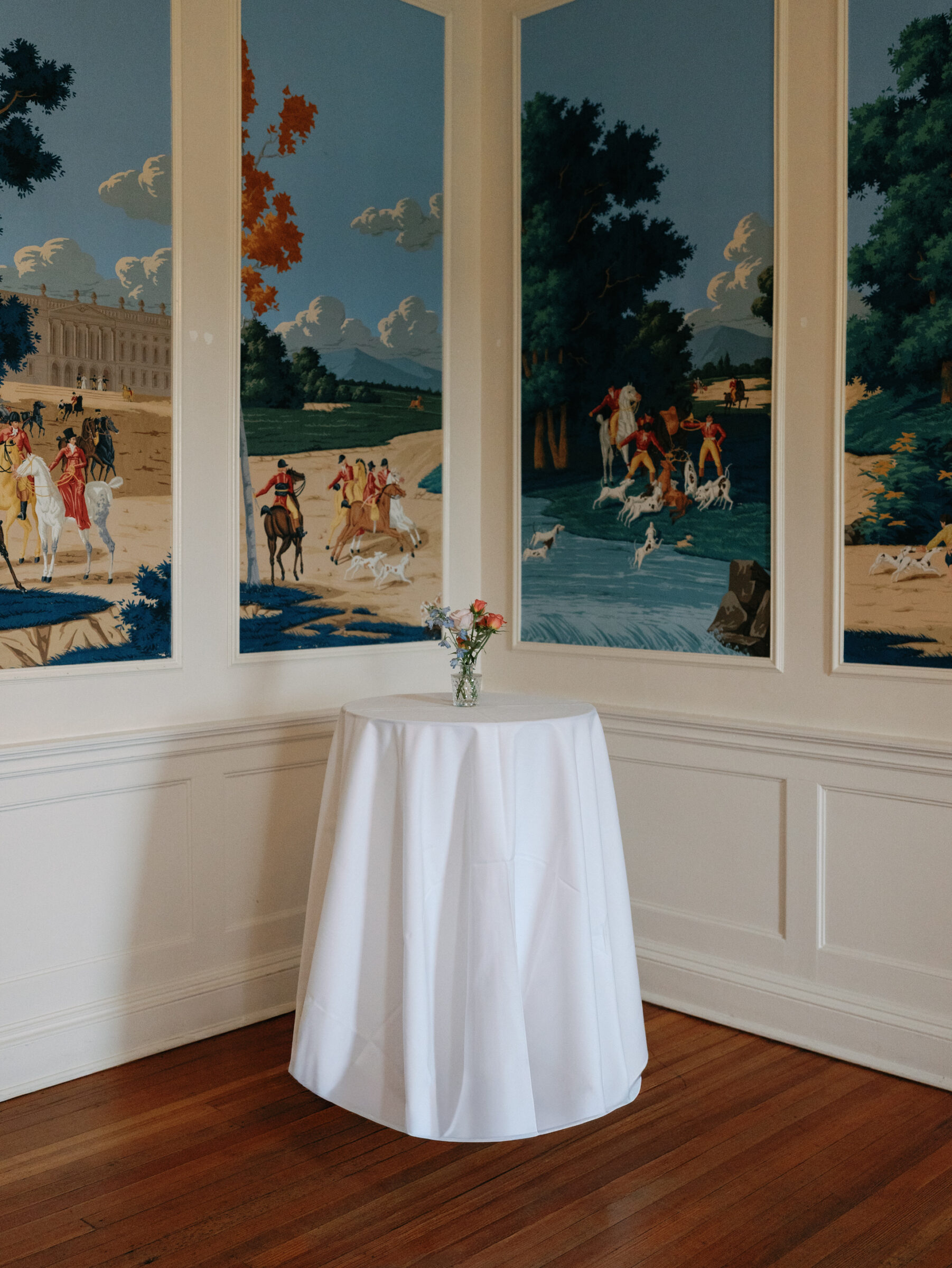 Cocktail table with floral centerpiece against historic mural walls inside Belmont Country Club in Ashburn, VA.