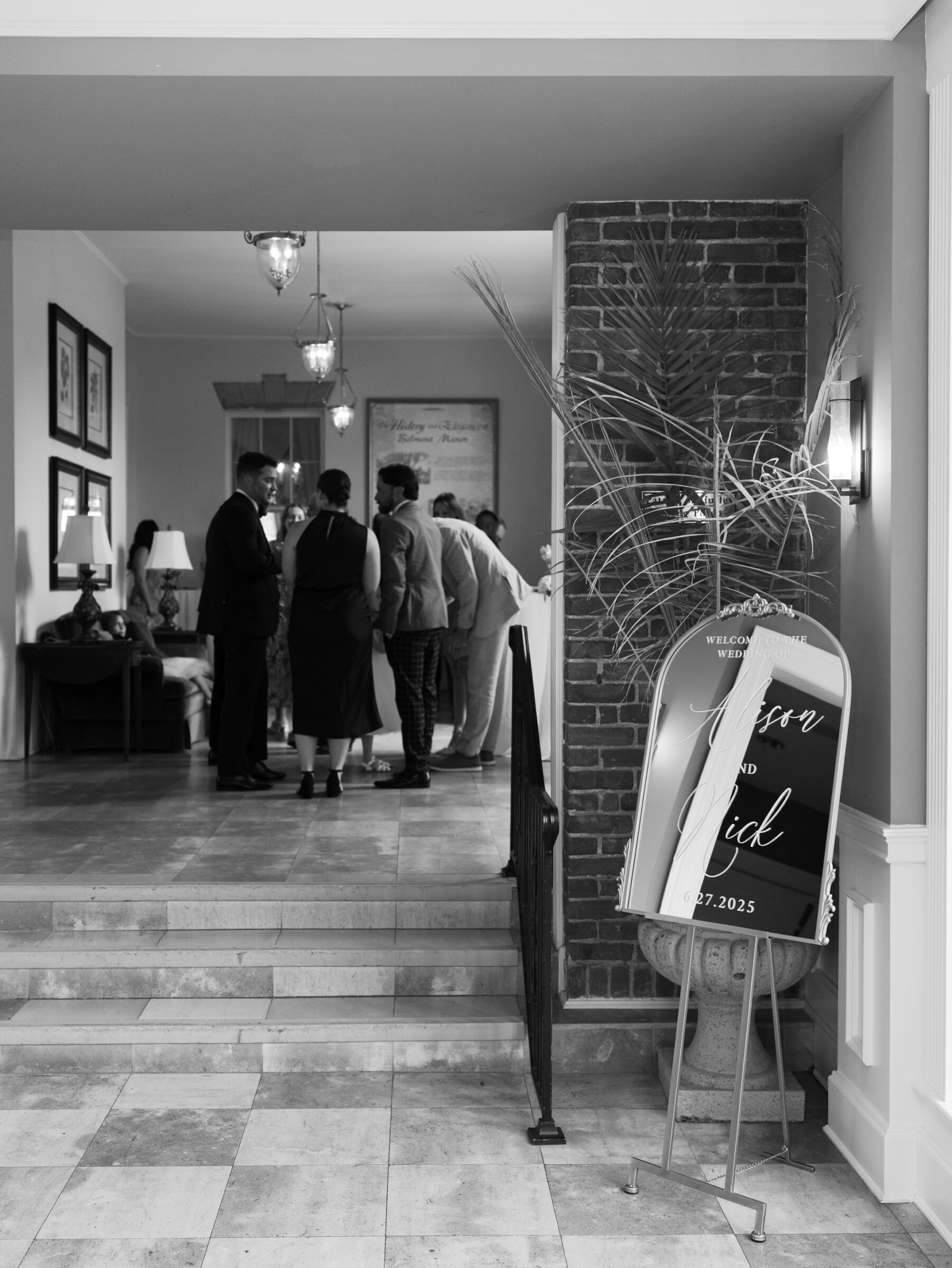Wedding guests gather inside Belmont Country Club near a modern mirror welcome sign in Ashburn, VA.