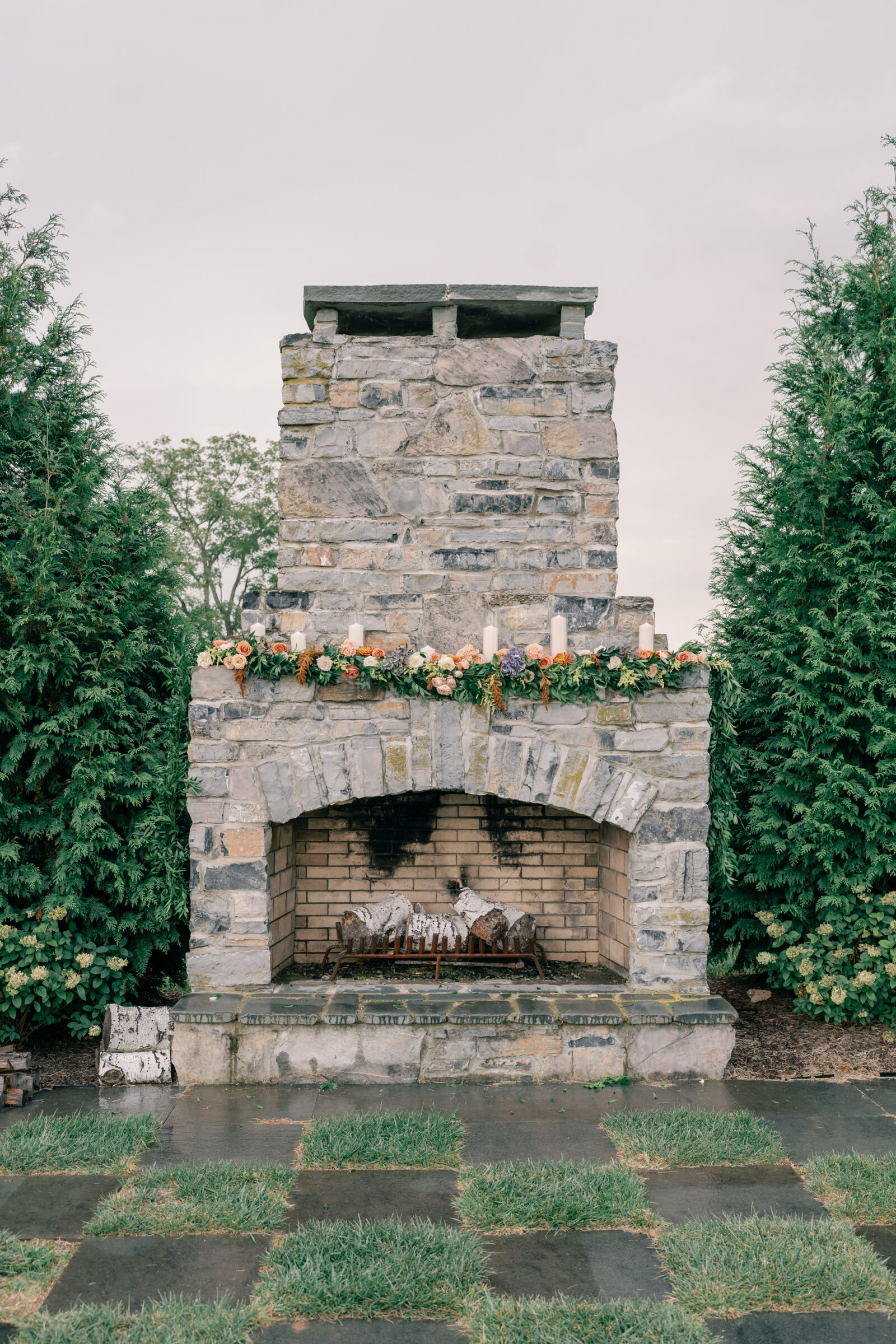 Stone outdoor fireplace decorated with candles and floral garland at Red August Farm wedding in Waynesboro VA