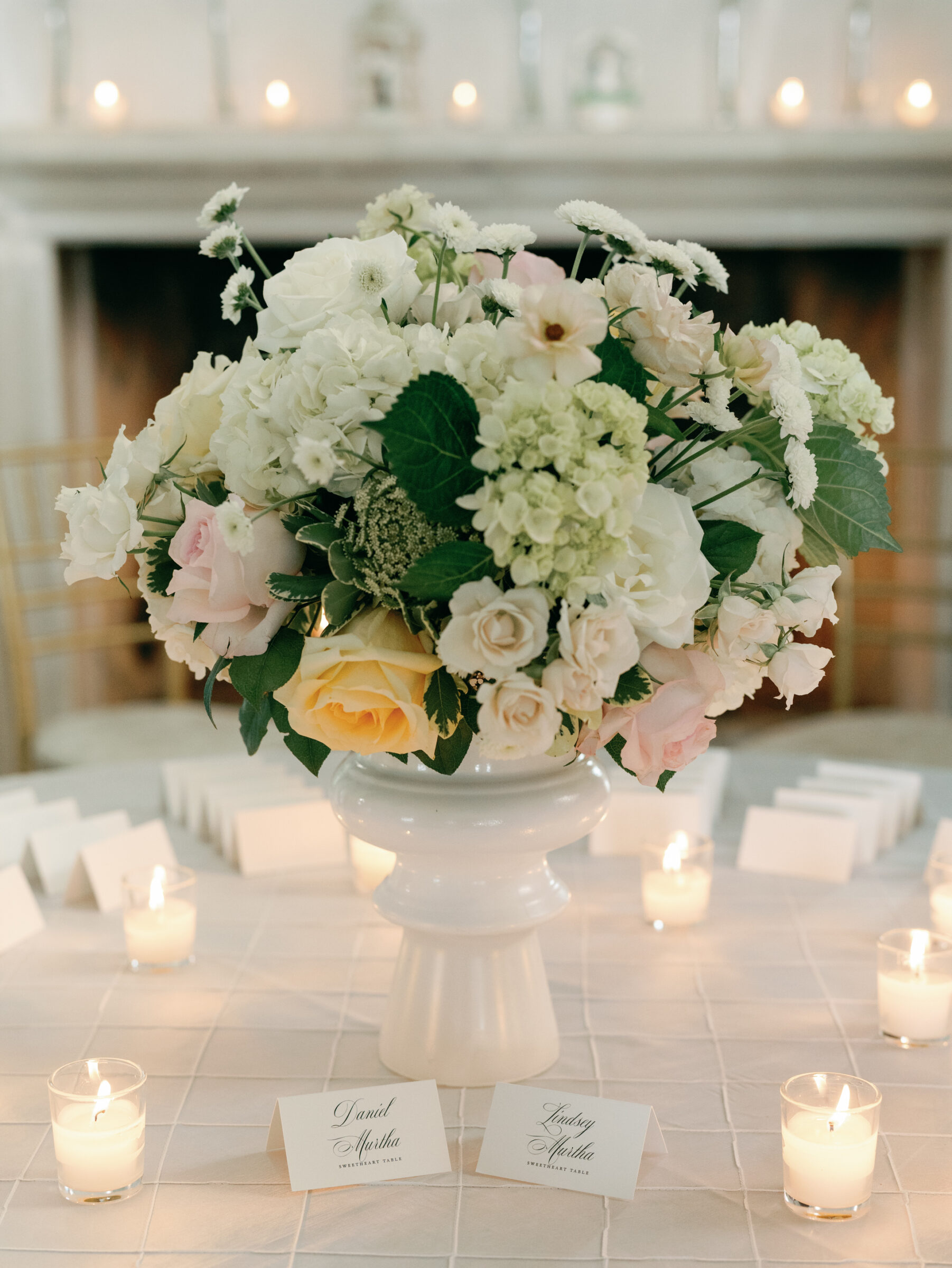 Romantic escort card display with pastel florals and glowing candles at a summer The View at Bluemont Wedding.