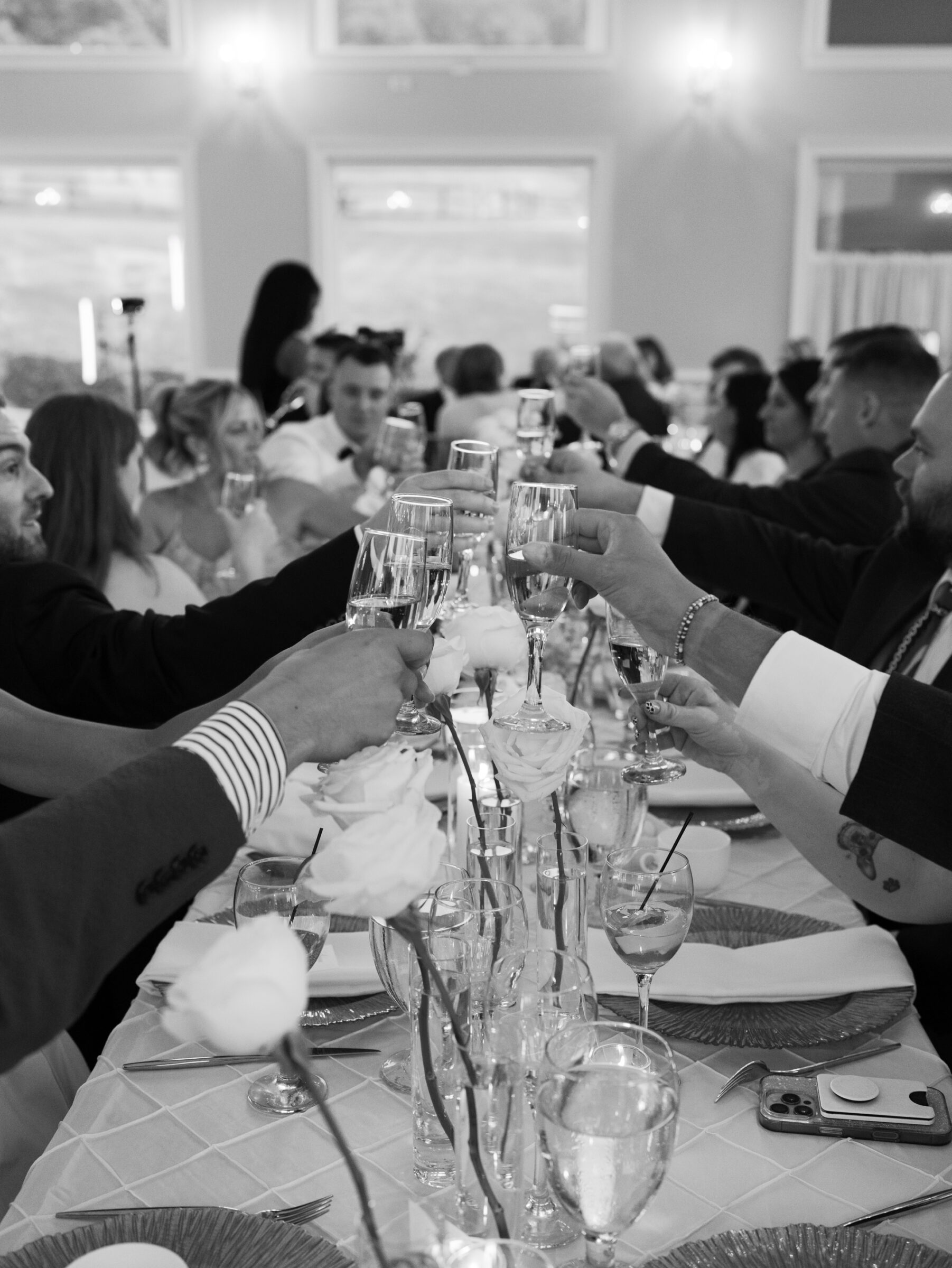 Candid group toast among guests at a romantic The View at Bluemont Wedding with florals and candlelight on the table.