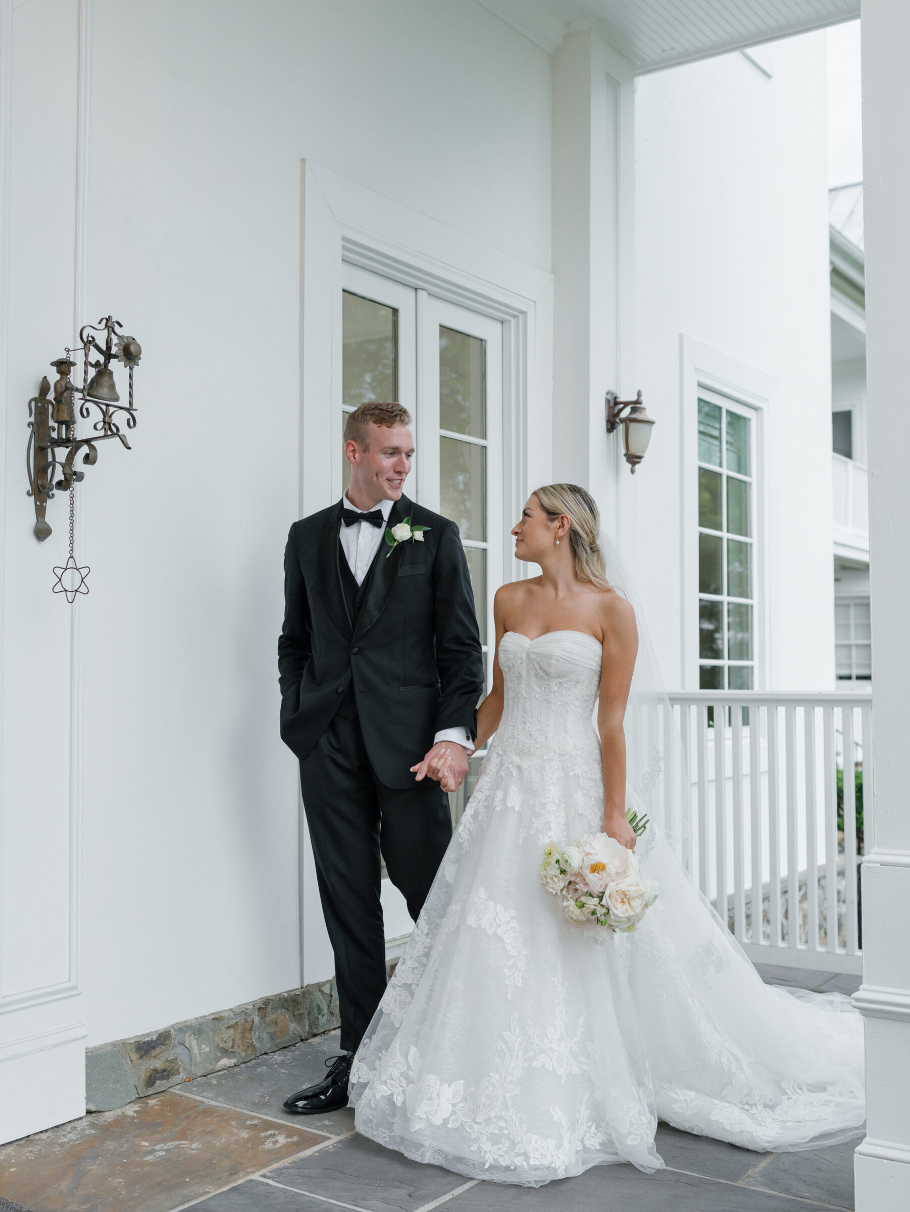 Bride and groom walking hand in hand during a The View at Bluemont Wedding, with classic white architecture behind them.