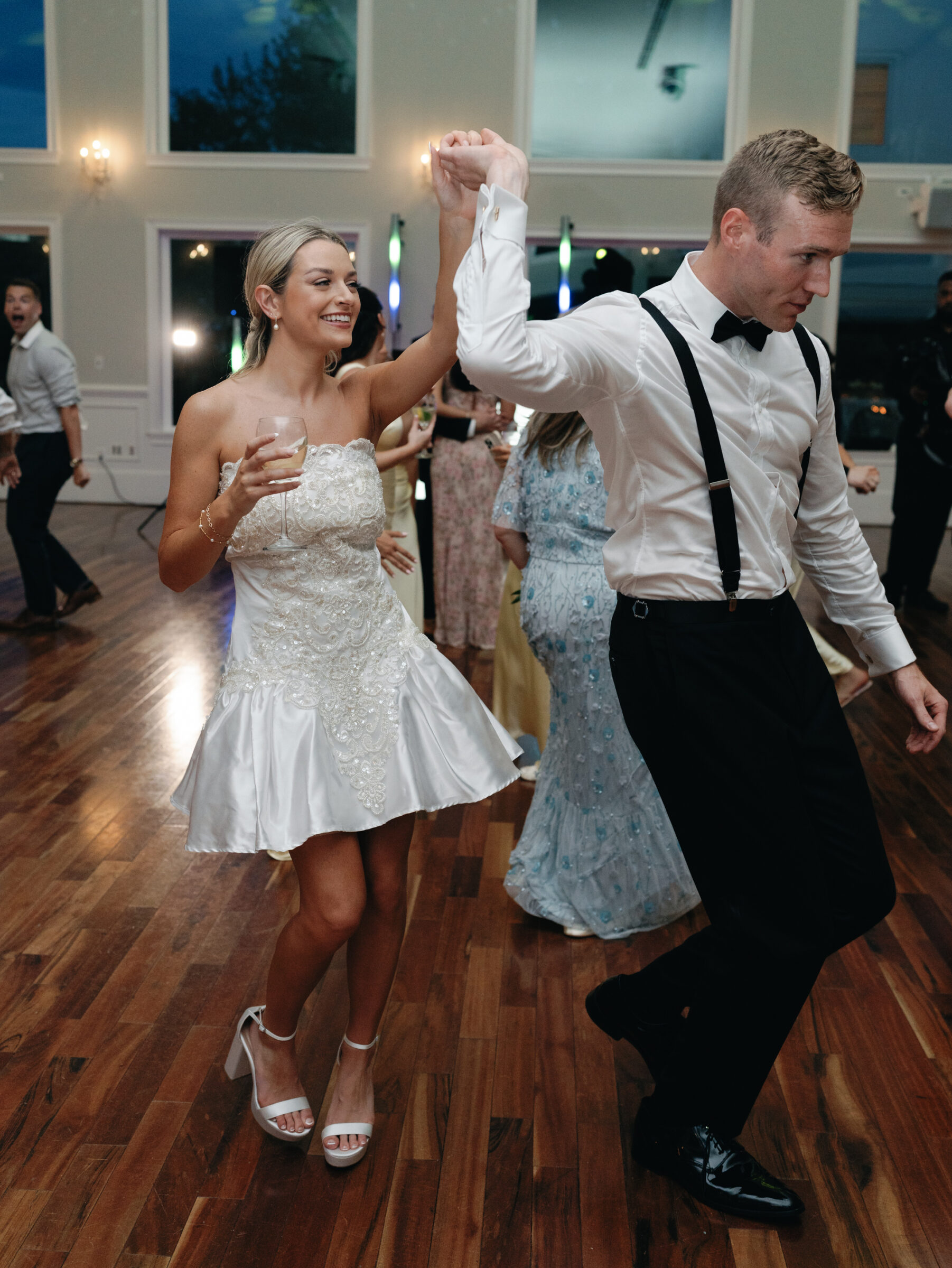 Newlyweds dancing during their reception at The View at Bluemont, with the bride in a short satin dress and the groom in suspenders.