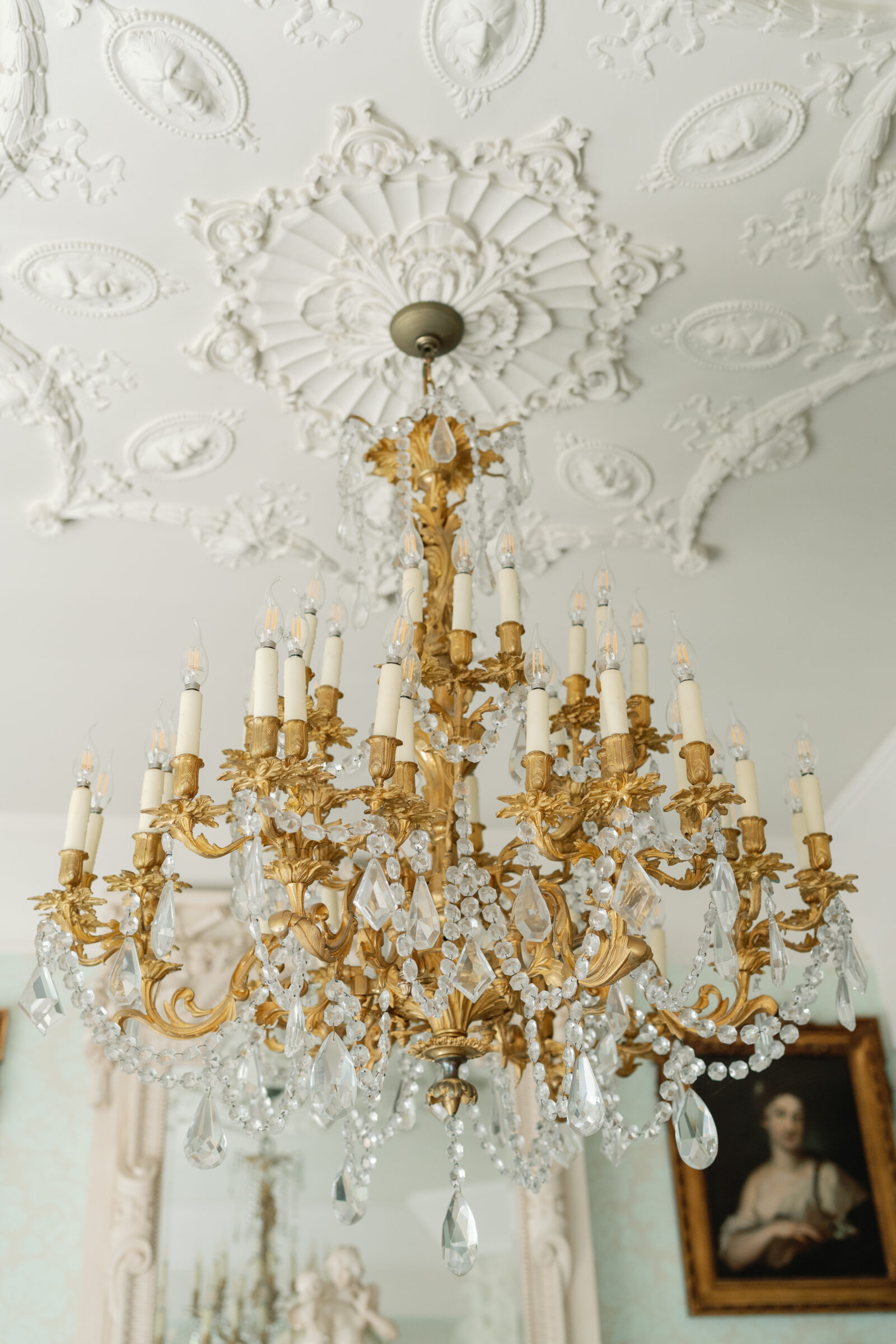 Close-up of Dover Hall’s ornate gold chandelier with crystal details and sculpted ceiling medallion.
