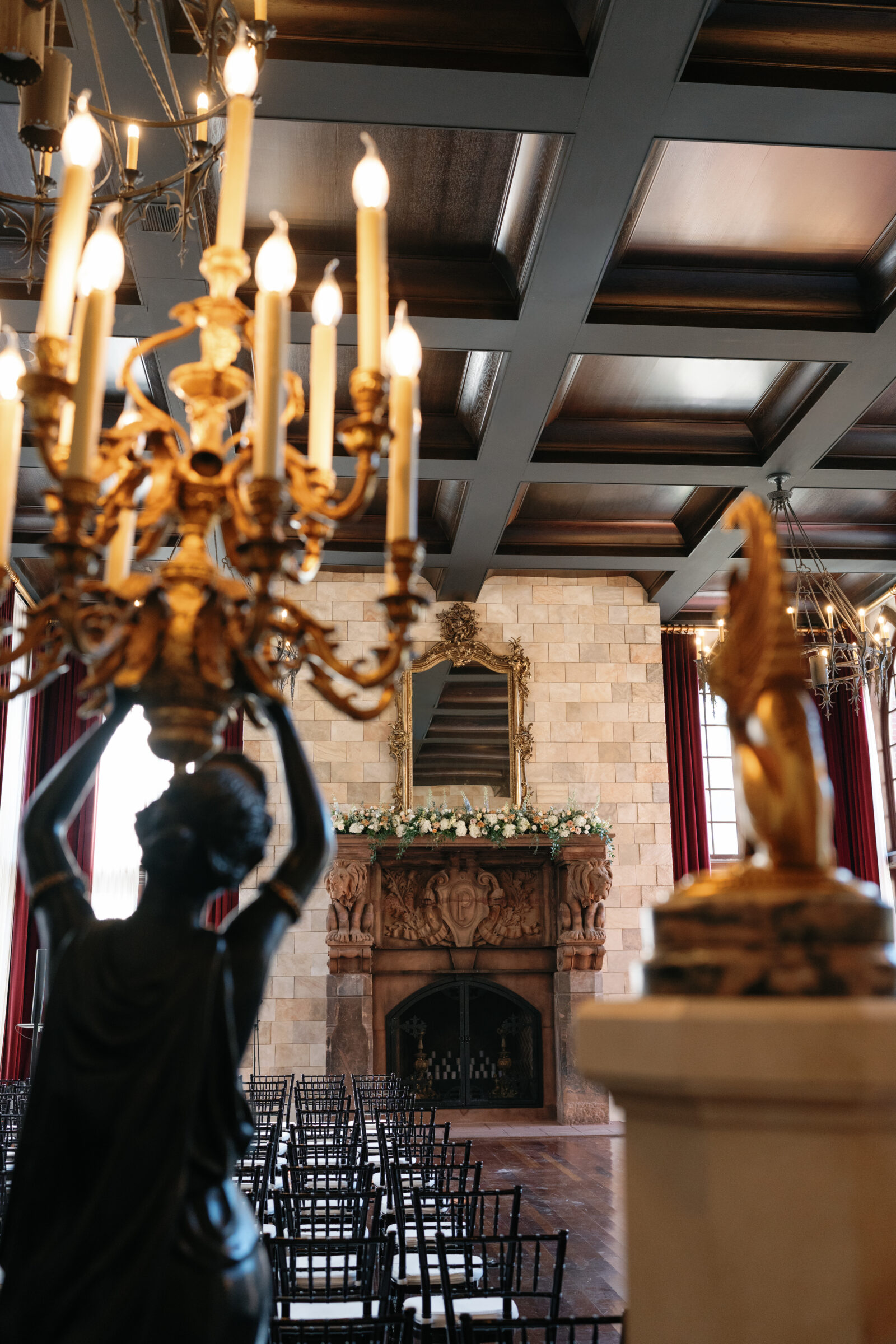 Ceremony setup inside Dover Hall featuring black chiavari chairs, floral arrangements on the grand fireplace, and ornate chandeliers — an elegant indoor ceremony space captured by a Richmond wedding photographer during a Dover Hall wedding.