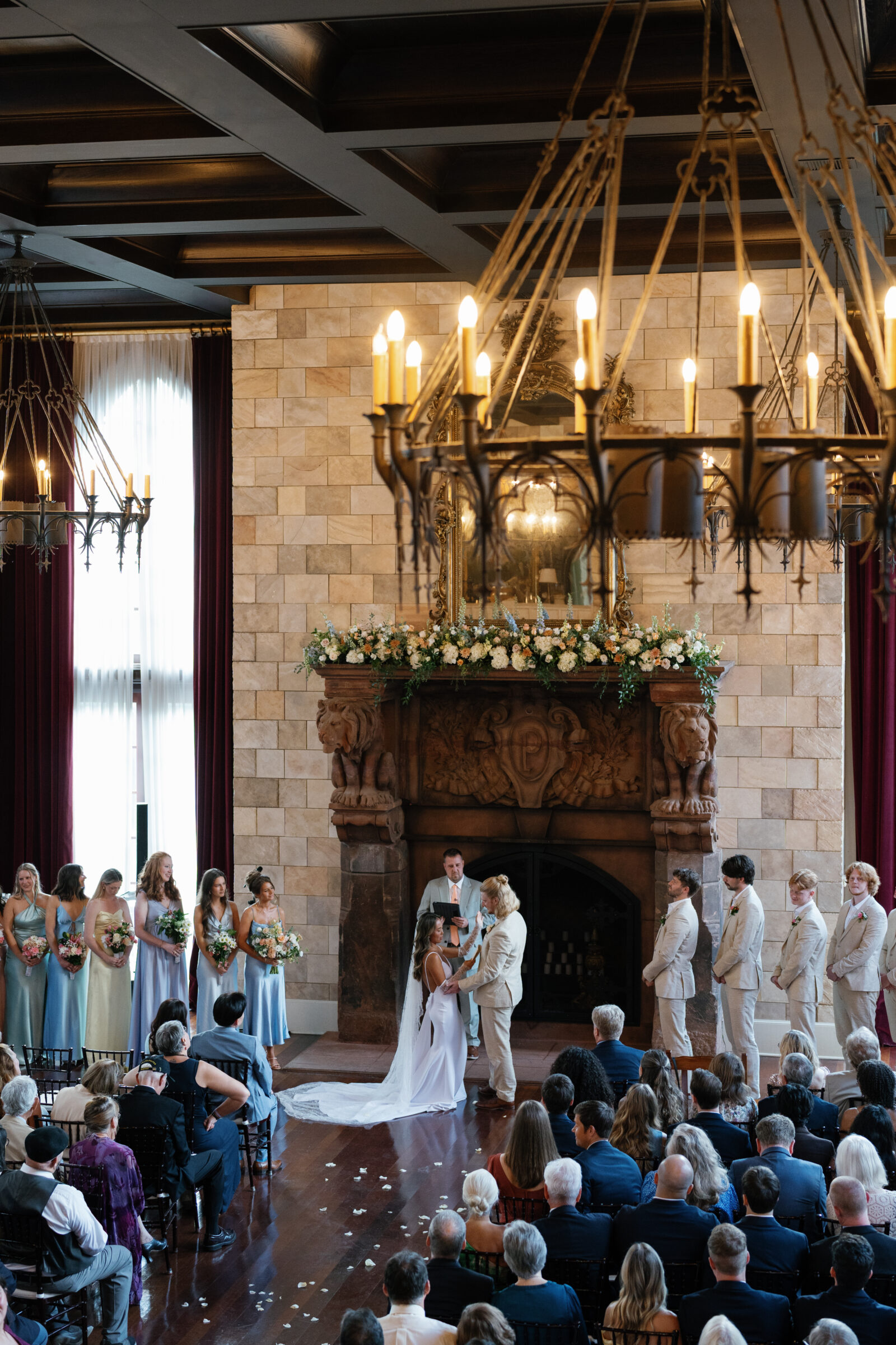 Wedding ceremony at Dover Hall with the couple exchanging vows before the grand fireplace, surrounded by pastel-clad bridesmaids and khaki-suited groomsmen — captured by a Richmond wedding photographer.