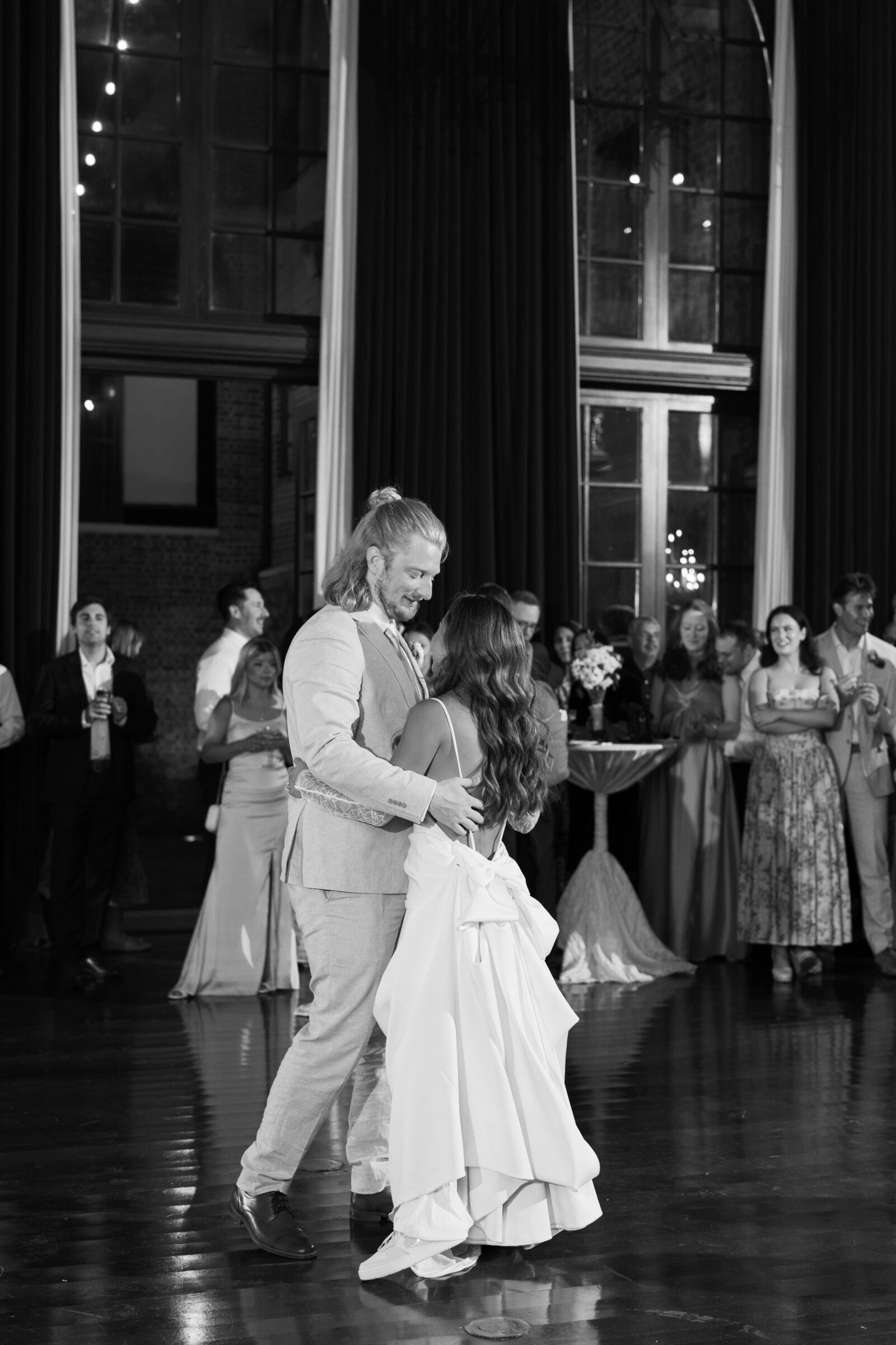 Bride and groom sharing their first dance inside Dover Hall, surrounded by guests and illuminated by soft, romantic lighting — a heartfelt celebration moment captured by a Richmond wedding photographer during a Dover Hall wedding.