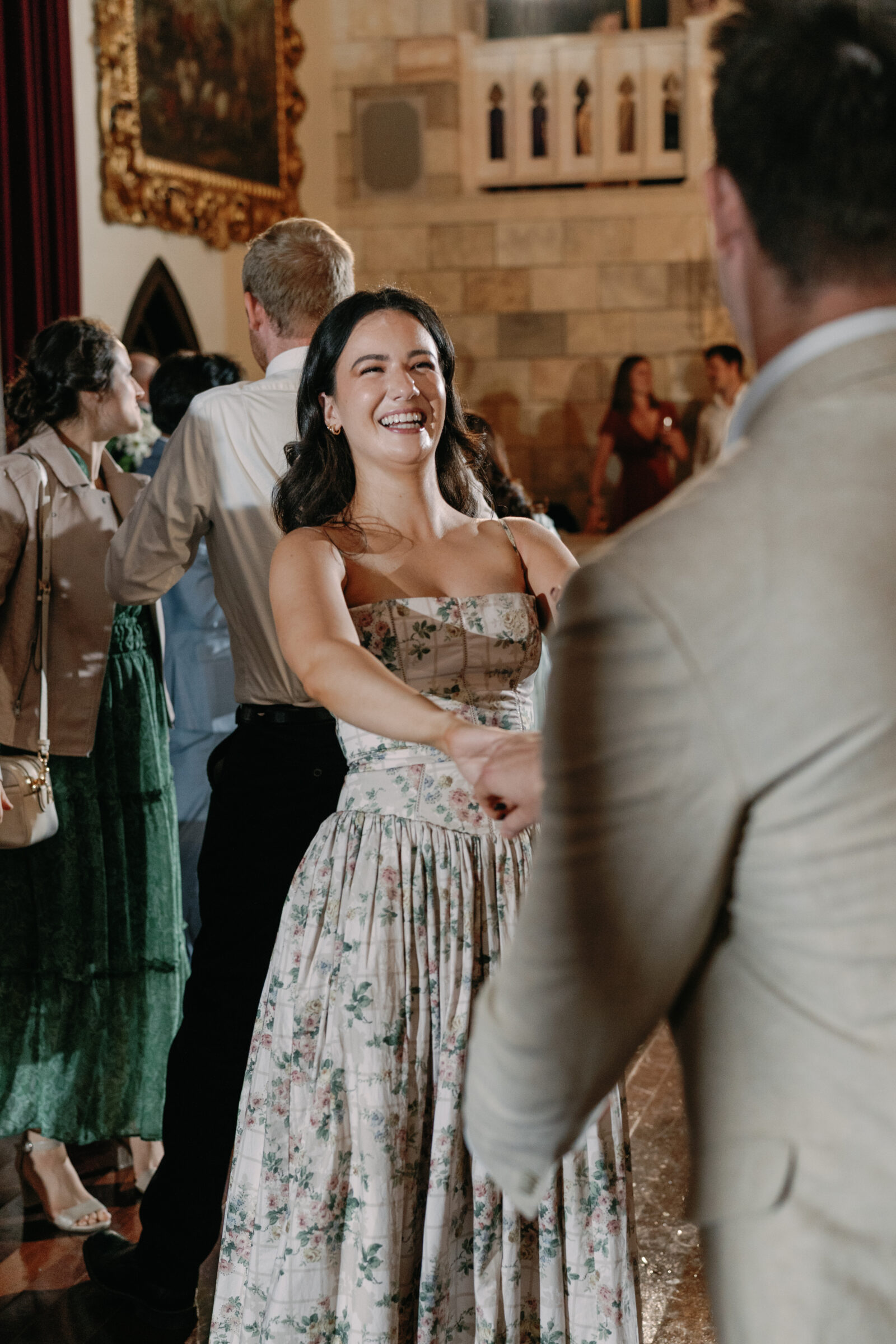 Wedding guest laughing and dancing during the reception inside Dover Hall, surrounded by warm lighting and elegant architecture — a joyful celebration moment captured by a Richmond wedding photographer during a Dover Hall wedding.
