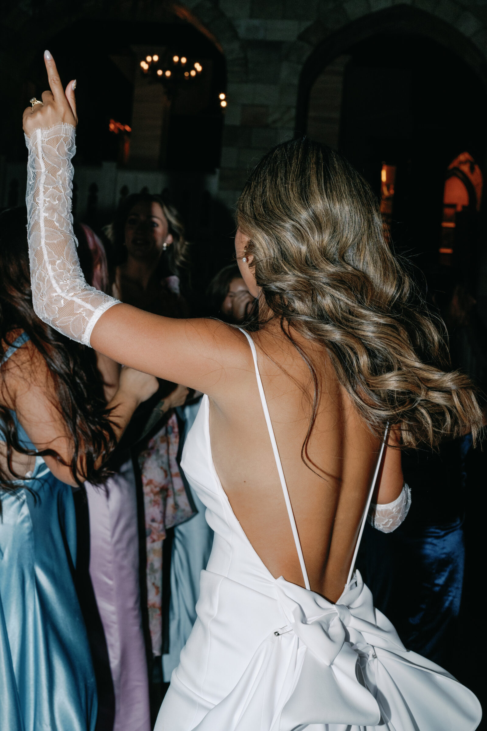 Bride dancing during the wedding reception at Dover Hall, wearing a backless gown with a statement bow and lace gloves — a joyful and elegant moment captured by a Richmond wedding photographer.