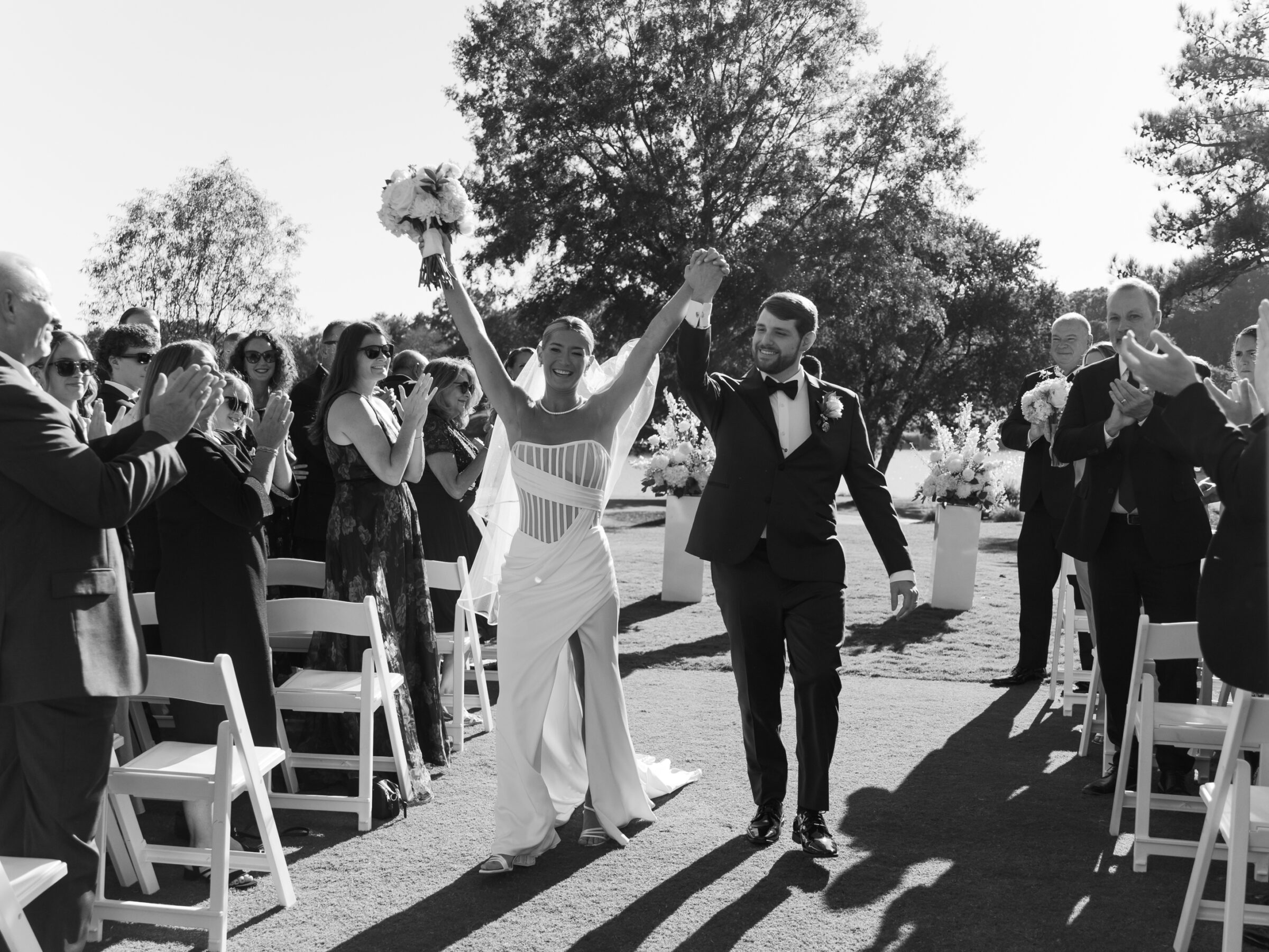 Hermitage Country Club Wedding | Bride and groom celebrating as they walk back up the aisle while guests cheer during their outdoor ceremony.