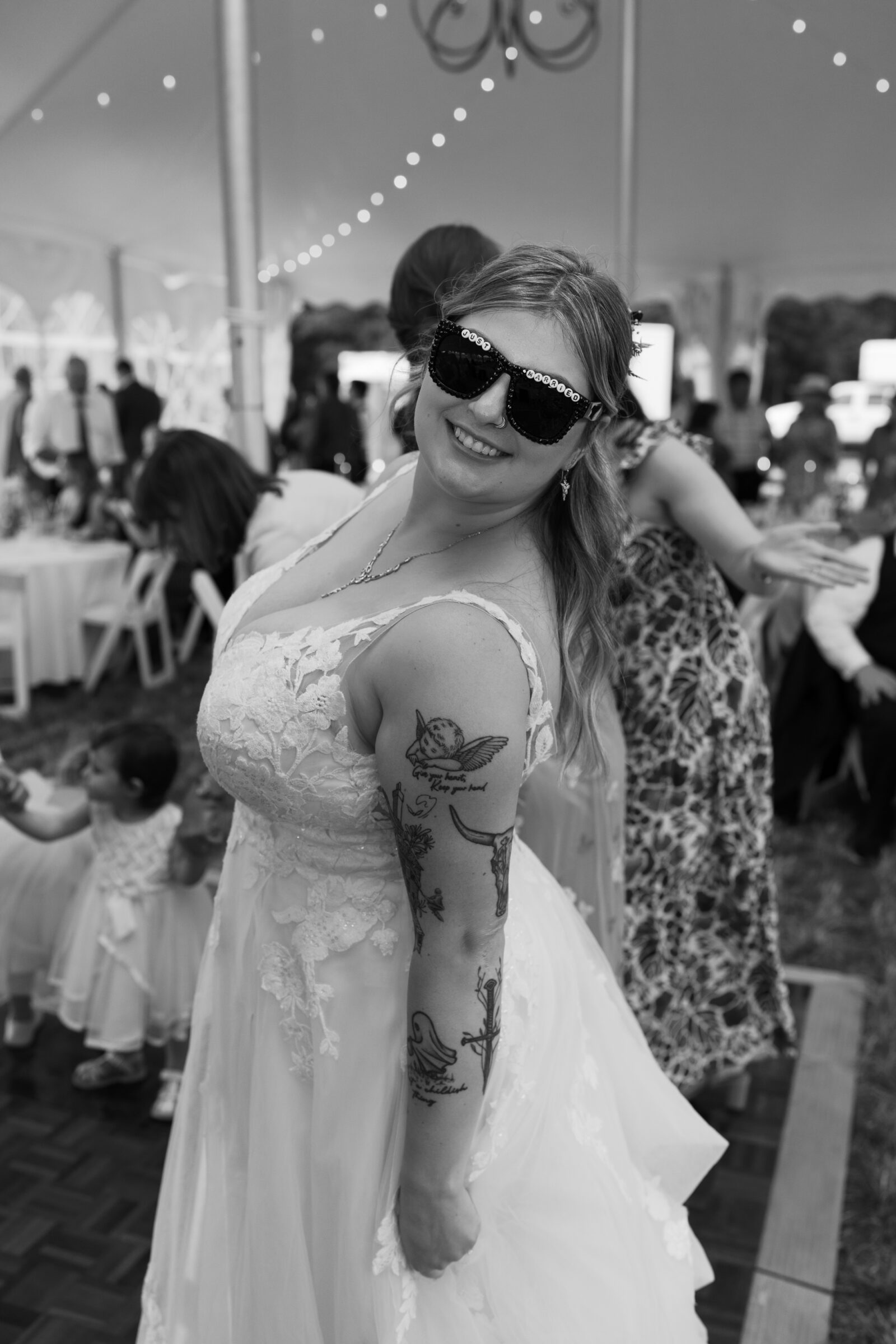 The bride smiles on the dance floor, wearing fun embellished sunglasses during the reception.