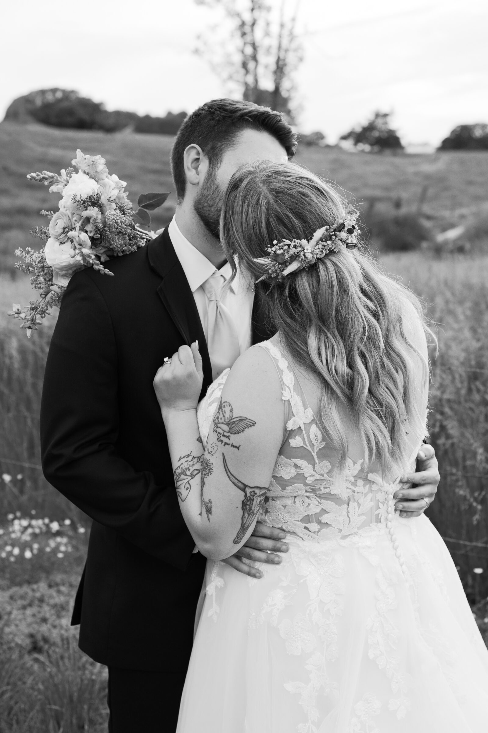 Southern Maryland Wedding Photographer | The couple shares a quiet kiss in the field, the bride’s floral hairpiece and bouquet adding soft detail to the moment.