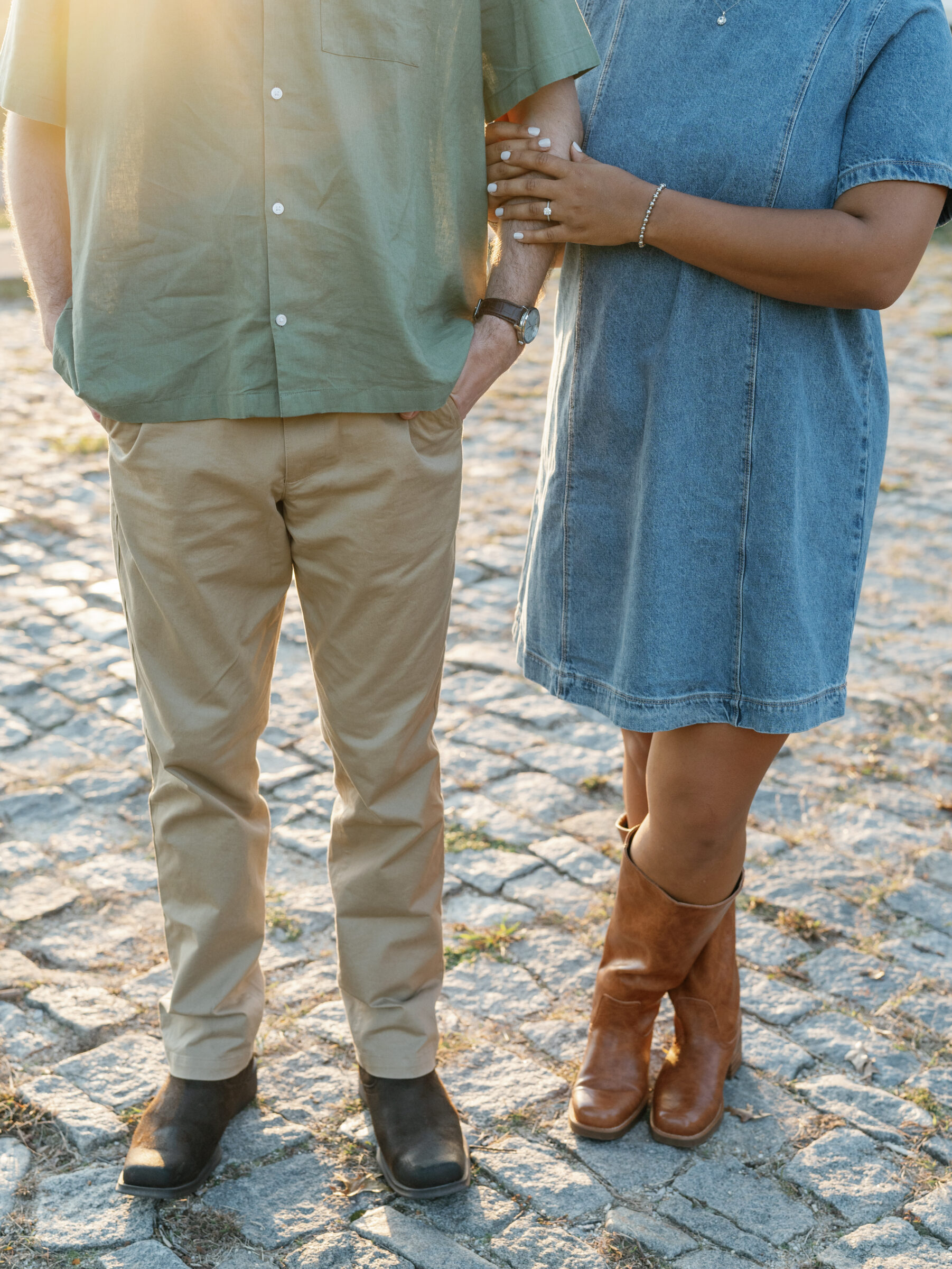 A close-up of a couple standing on the cobblestones at Libby Hill Park, with her hand resting on his arm and the golden sunlight highlighting her engagement ring.