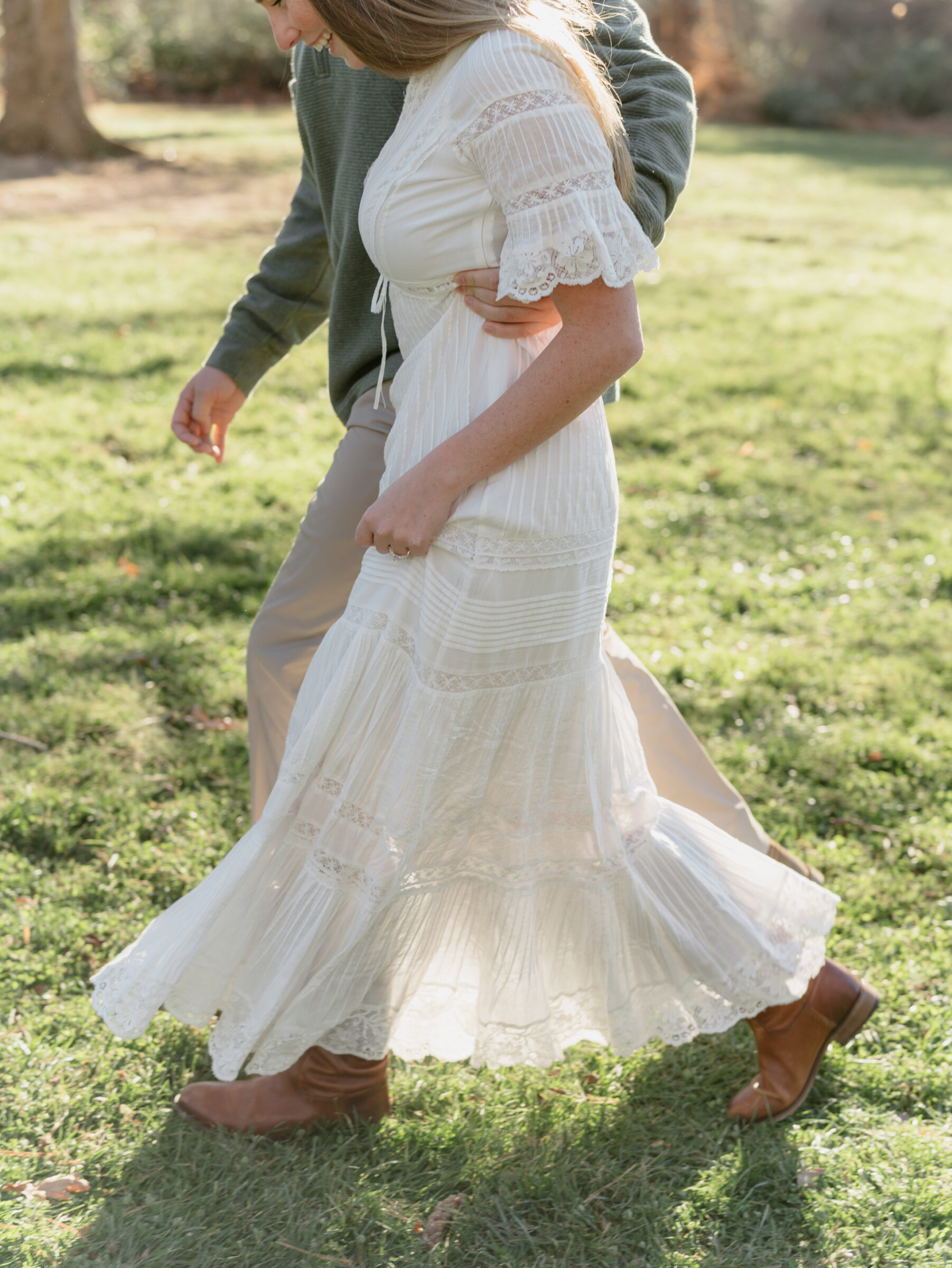 Bride in a flowing white dress walking with her fiancé during a fall engagement session at the Biltmore Estate
