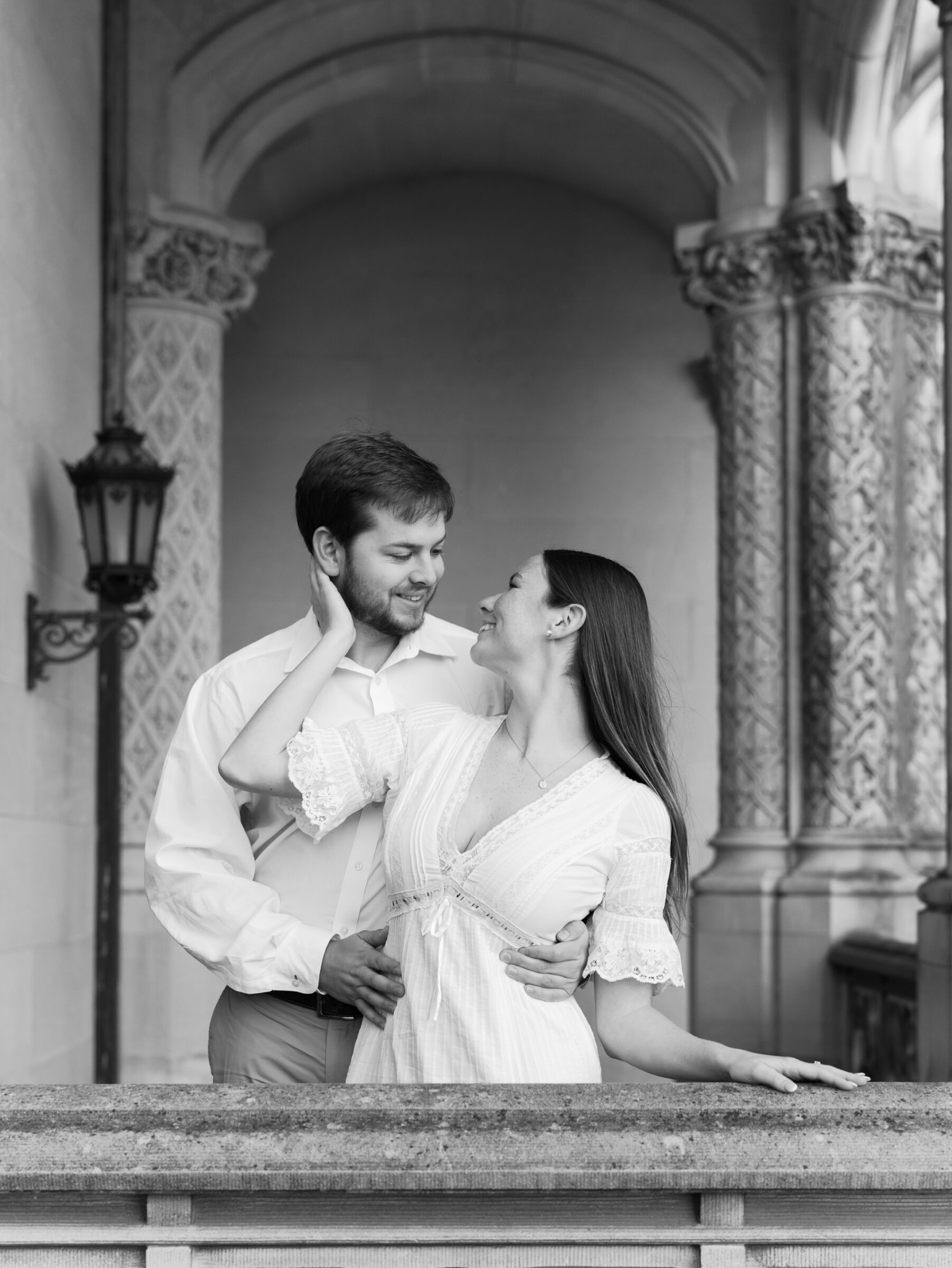 Black and white engagement portrait of a couple embracing beneath the arches at the Biltmore Estate in Asheville NC