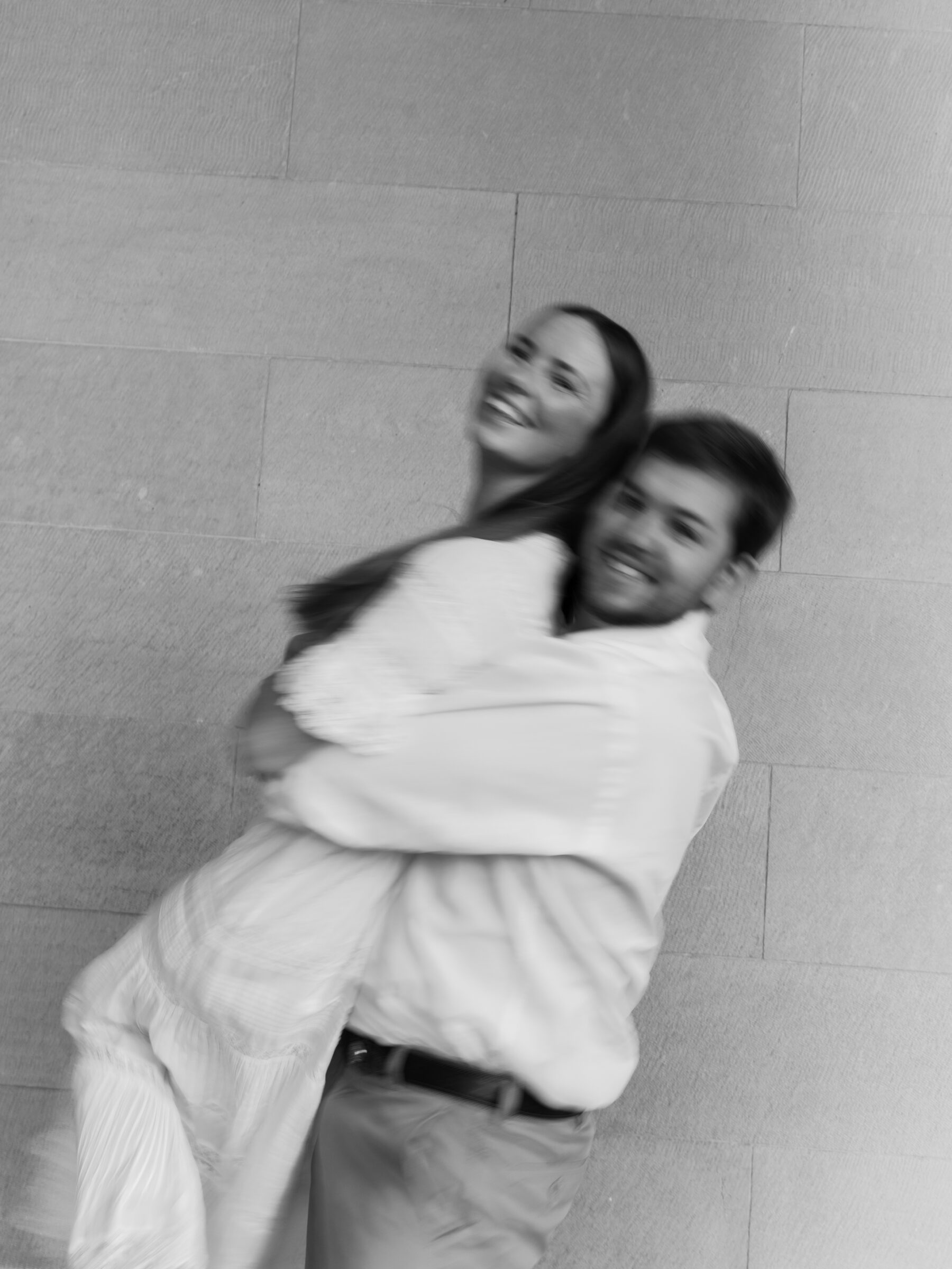 Black and white candid of a couple laughing together during a playful engagement moment